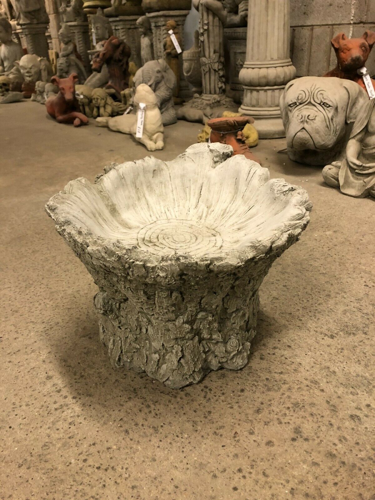 Front-facing view of stone tree stump bird bath with wide, shallow bowl, ideal for attracting birds to garden or patio areas.