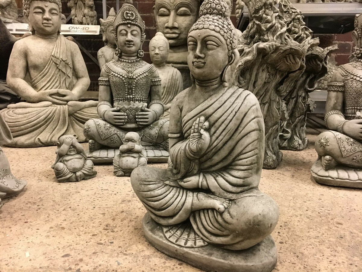 Stone Jnana Mudra Buddha Statue surrounded by other sculptures, showcasing its serene expression and durable weather-proof finish.