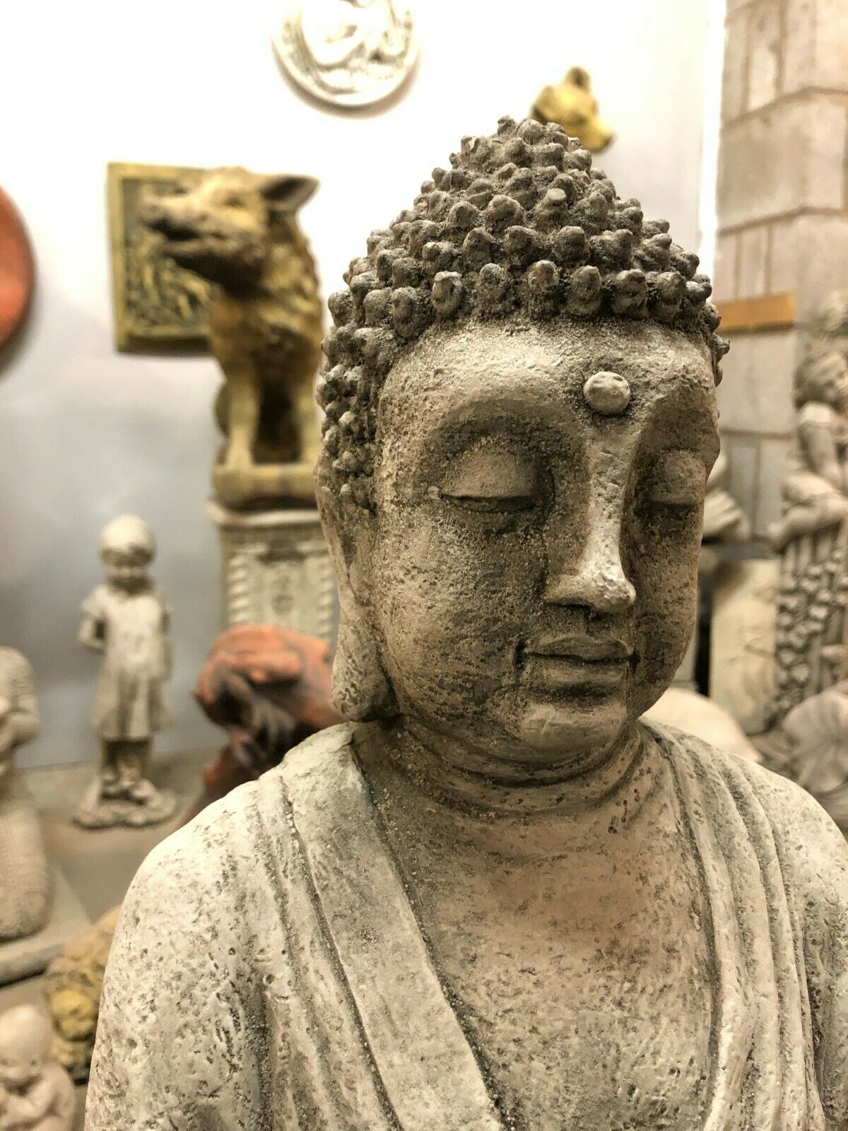 Headshot of stone Buddha statue with closed eyes and peaceful expression, ideal for tranquil garden spaces.