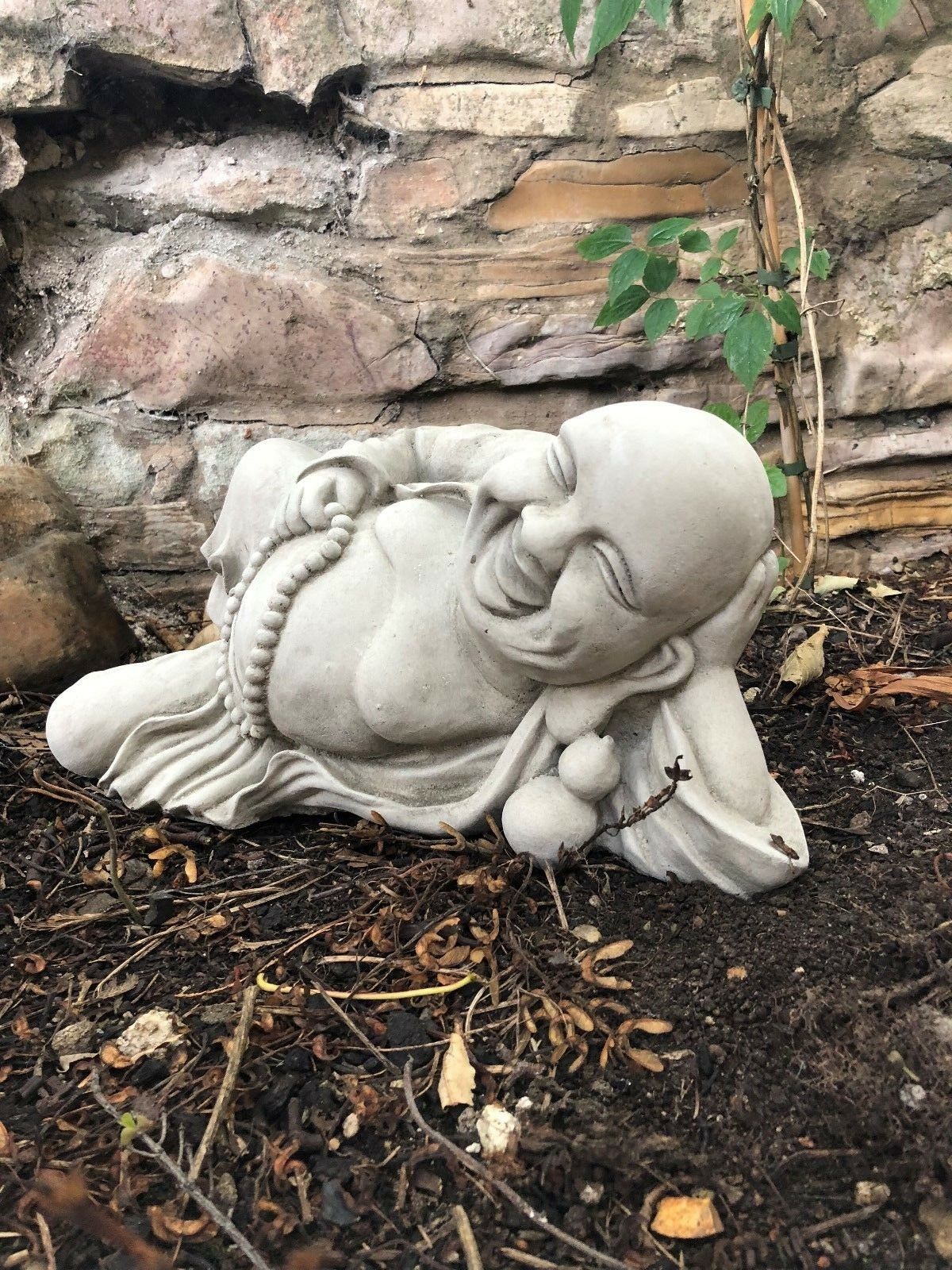 Close-up of Jolly Stone Buddha Garden Ornament resting on elbow, showcasing fine stone detailing and joyful expression.