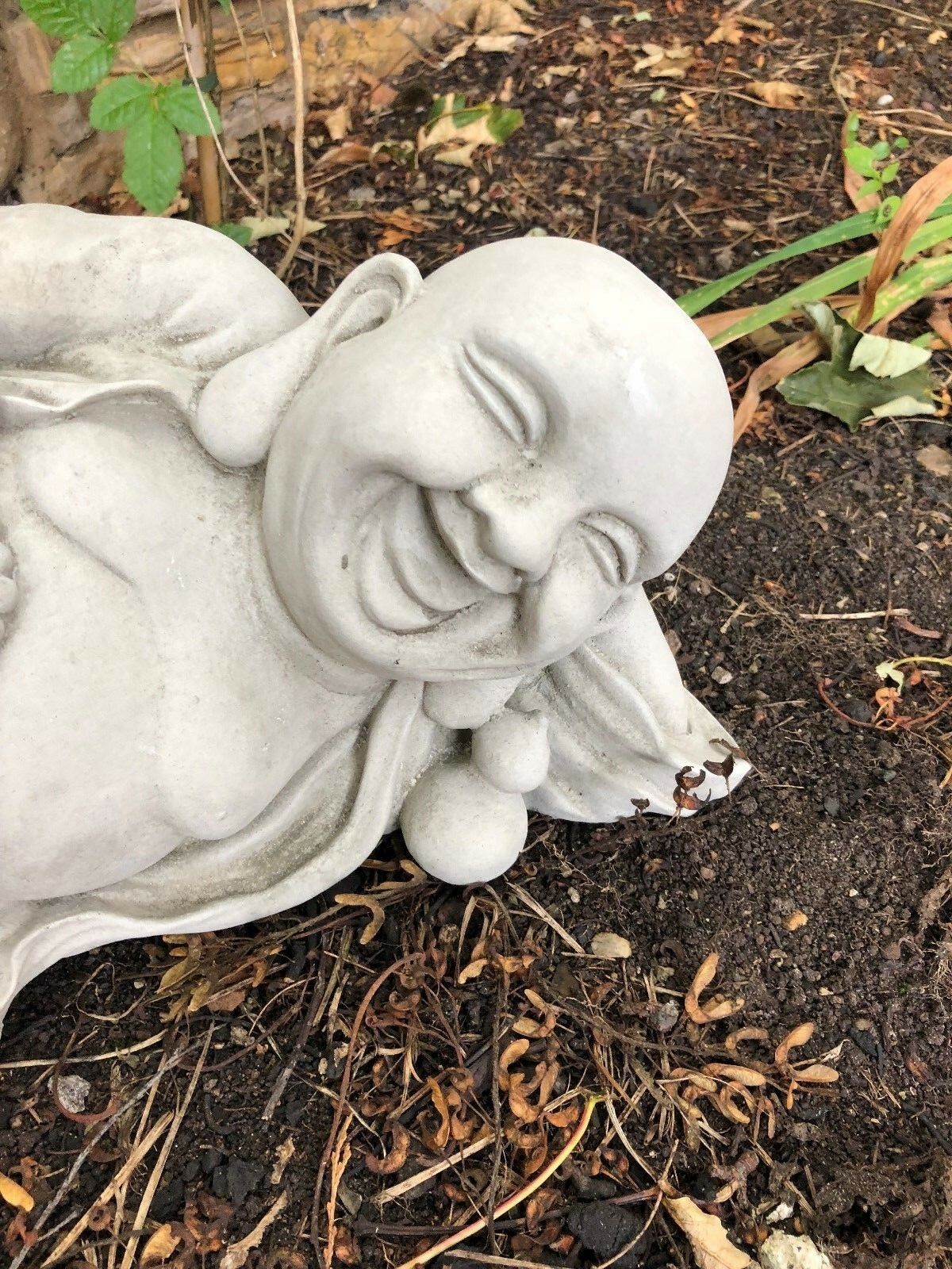 Smiling face of Jolly Stone Buddha statue with intricate stonework, designed to bring peace and charm to garden landscapes.