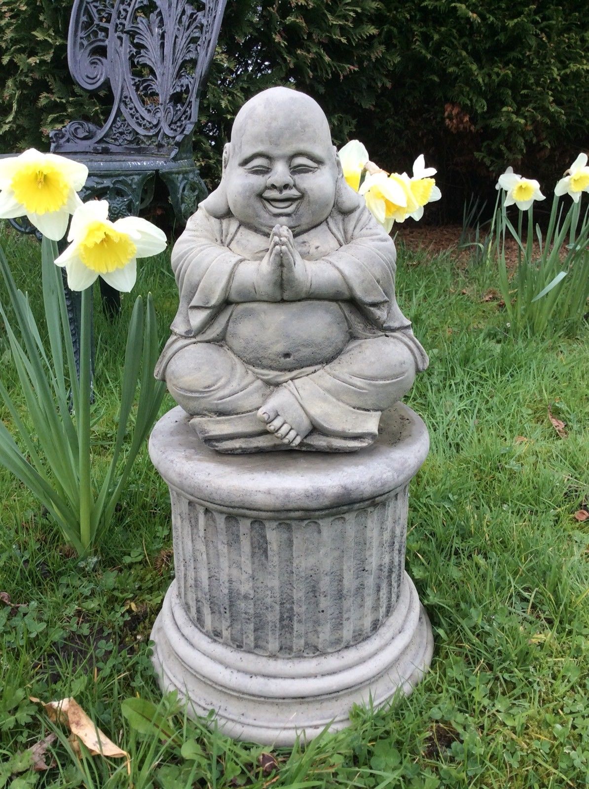 Happy Praying Buddha Statue in stone on a pedestal, ideal for garden decor. Durable and weather-resistant for outdoor bliss and spiritual charm.