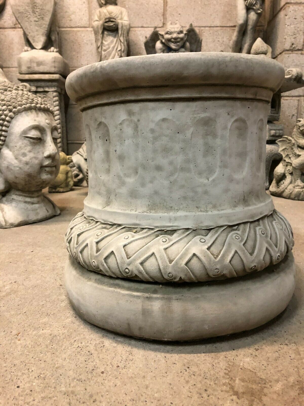 Close-up of solid stone garden plinth with carved detailing and weathered finish, designed for stability and timeless garden decor.