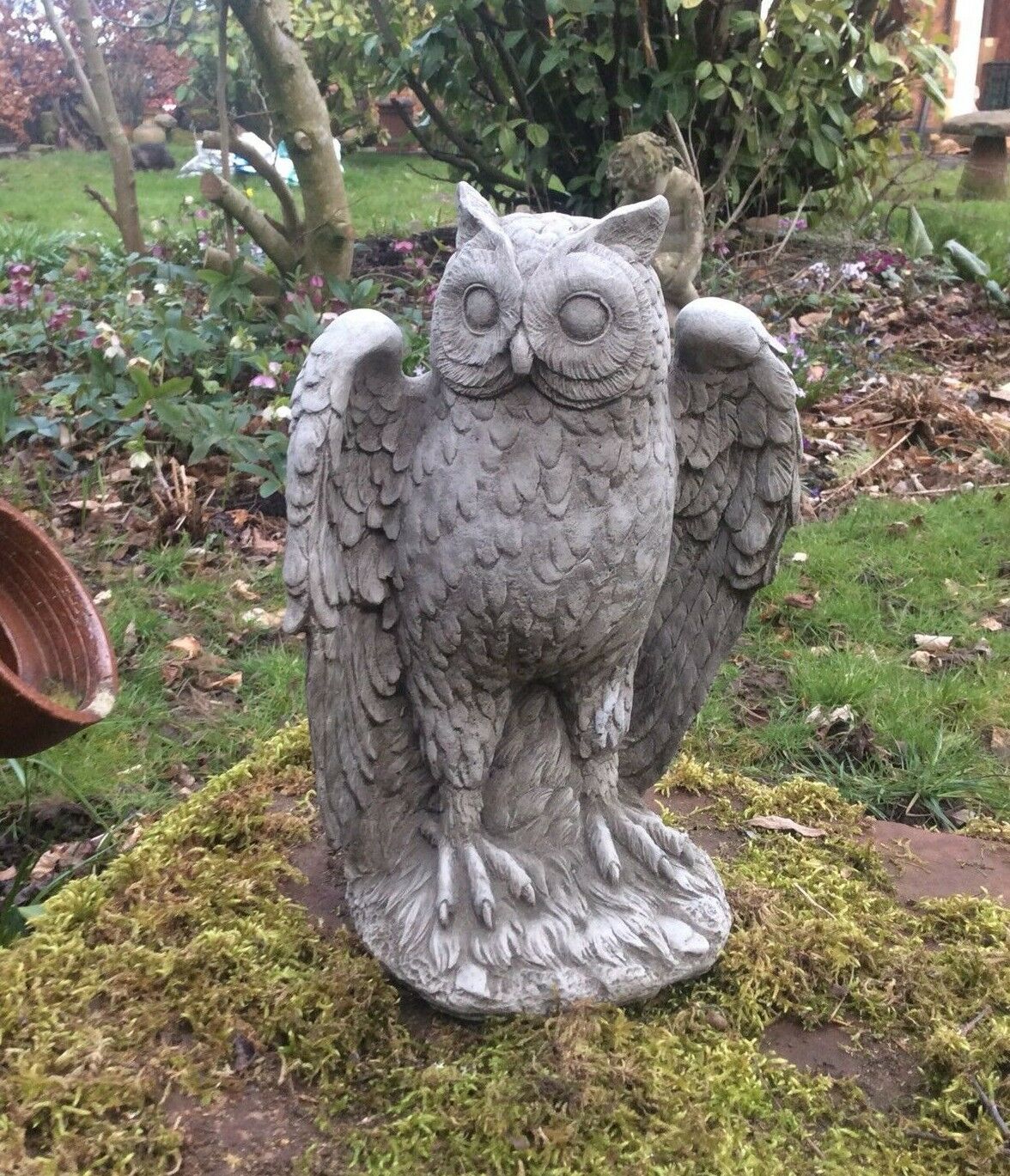 Stone Owl Garden Statue - Antique Weatherproof Finish with detailed wings and feathers, placed on mossy stone in a lush garden setting.