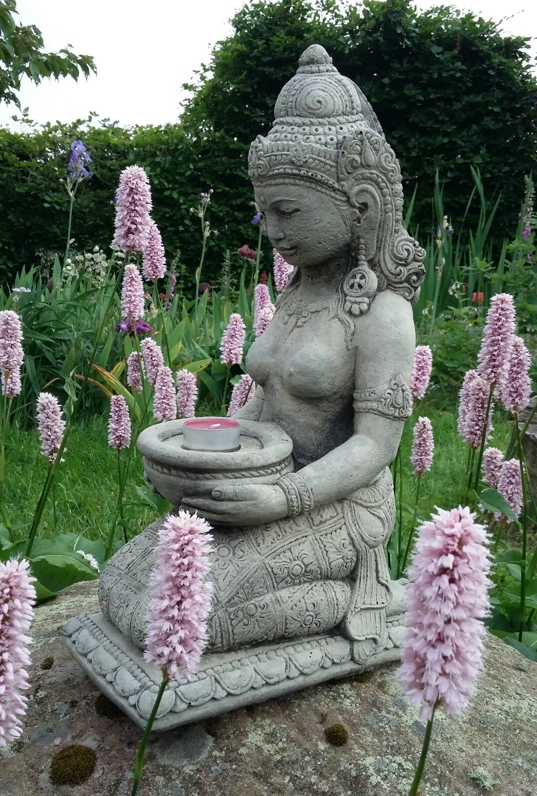 Geisha Statue Candle Holder - Stone Praying Geisha kneeling on a rock among pink flowers, holding a tealight bowl for garden decor.