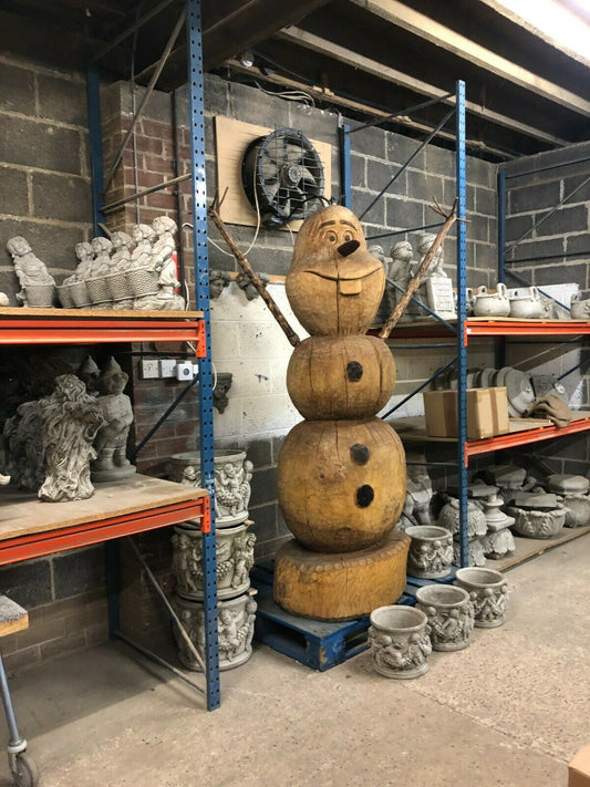 Handcrafted Wooden Olaf Statue - Garden Display standing tall in a workshop, surrounded by stone garden ornaments and sculptures.