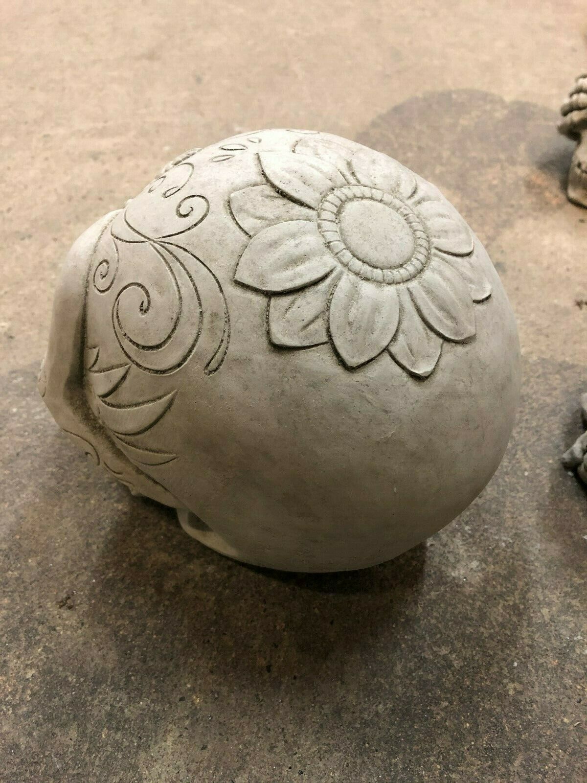 Top view of Stone Skull Garden Ornament showing large carved flower. Made from durable limestone with antique finish for outdoor use.