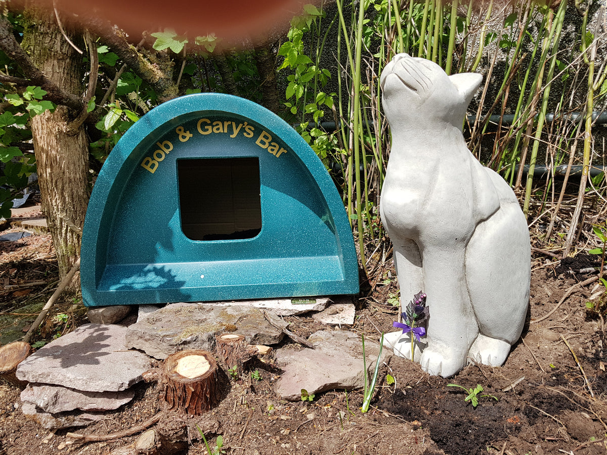 Stone Cat Garden Ornament - Durable Stone placed beside a garden bar, enhancing outdoor decor with a charming and artistic feline figure.