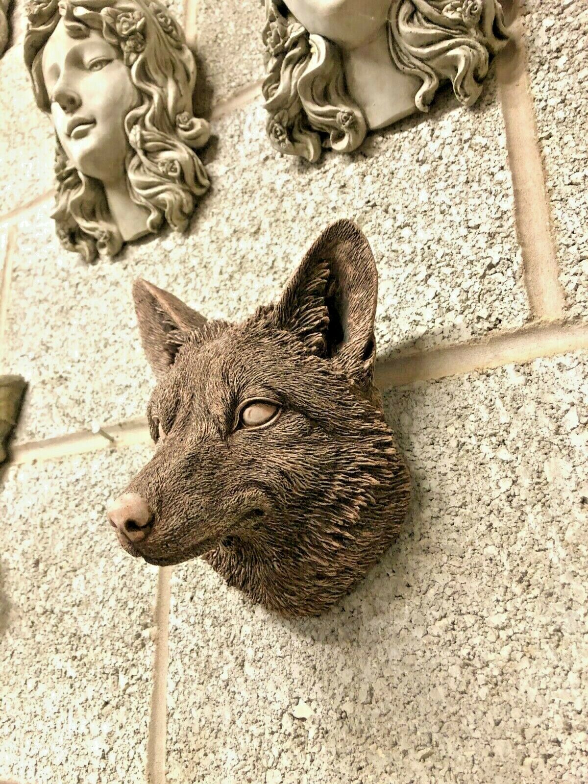 Angled view of Fox Head Garden Plaque on outdoor wall, surrounded by other decorative plaques, ideal for garden or patio decor.