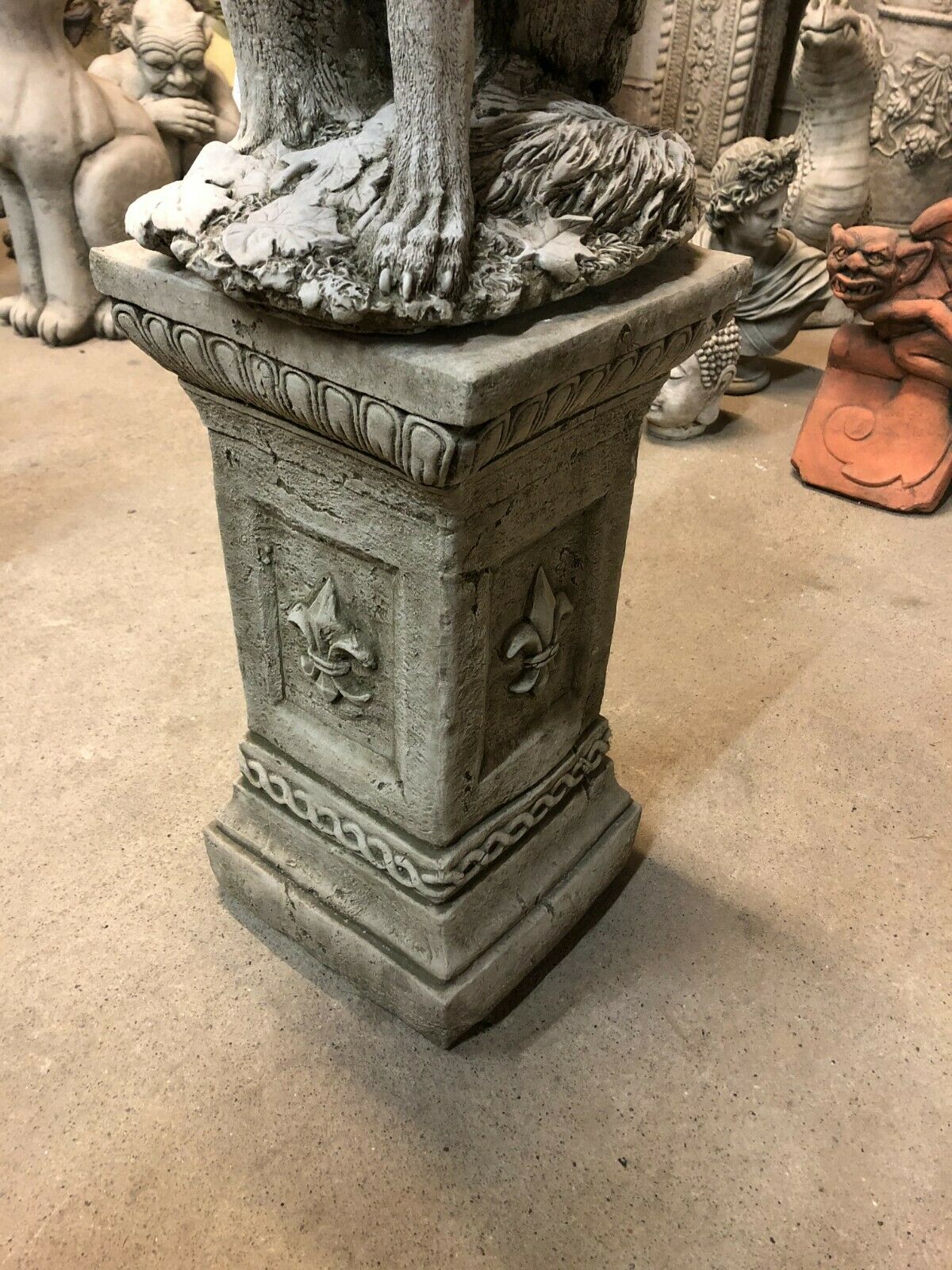 Close-up of stone pedestal base with fleur-de-lis design supporting the Howling Wolf Garden Statue, ideal for rustic outdoor decor.