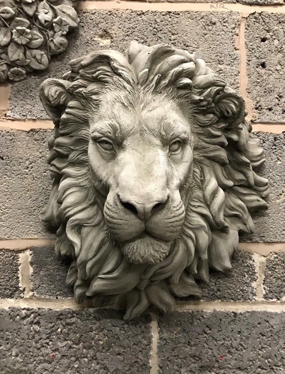 Stone King Lion Wall Plaque with antique limestone finish, mounted on a brick wall. Ideal for garden or patio decor with regal detailing.