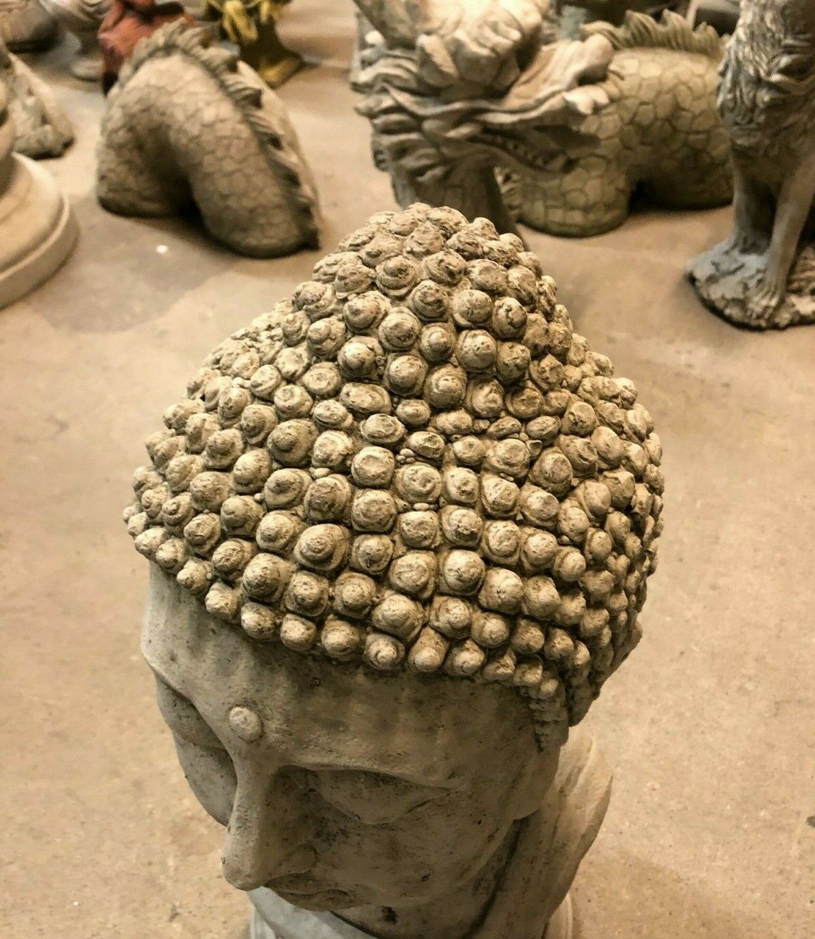 Top view of large stone Buddha head showing intricate hair detail. Durable limestone statue for outdoor garden decoration.