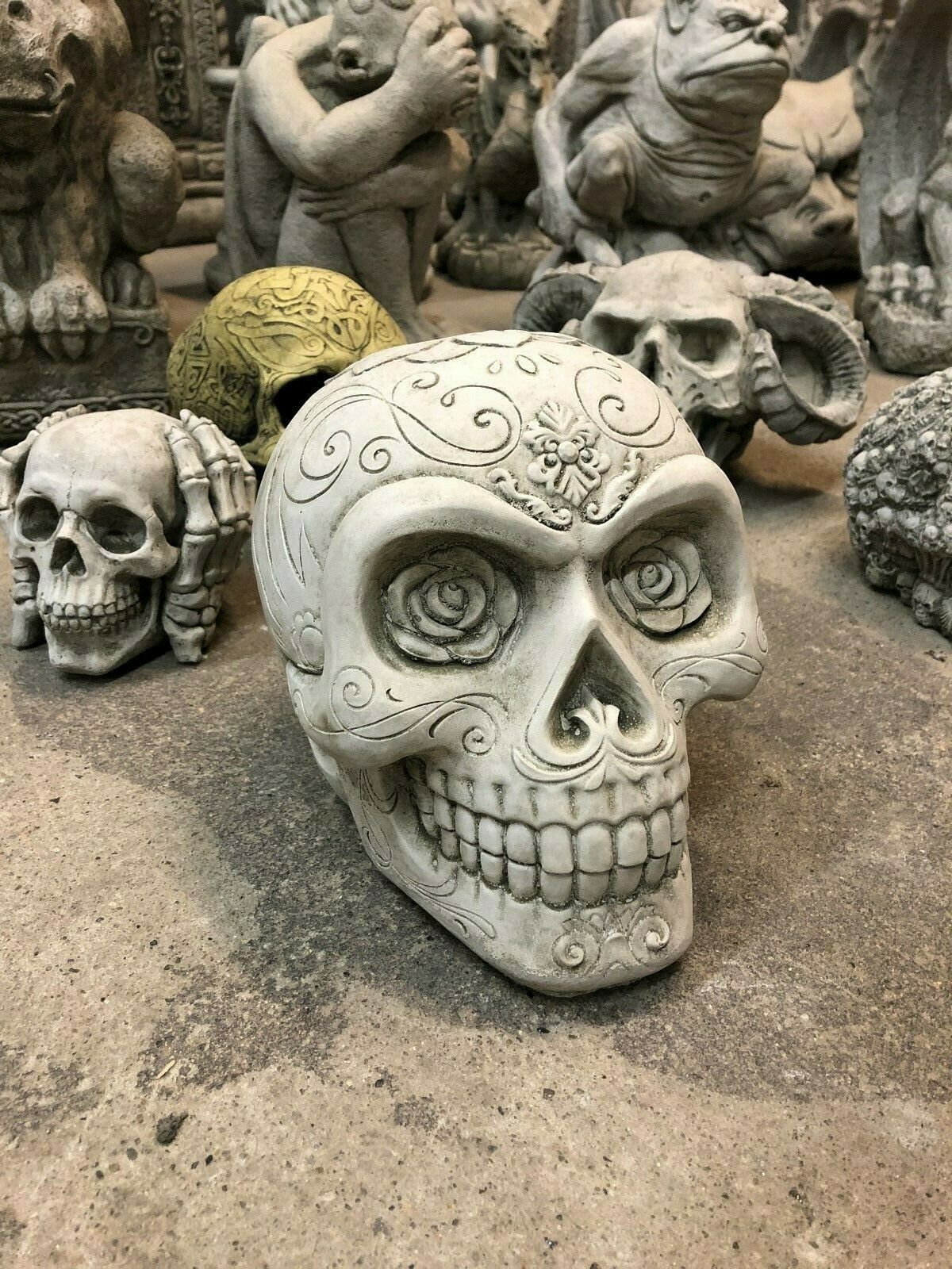 Decorative Stone Skull Garden Ornament with floral and swirl engravings. Antique finish and solid build for unique garden styling.