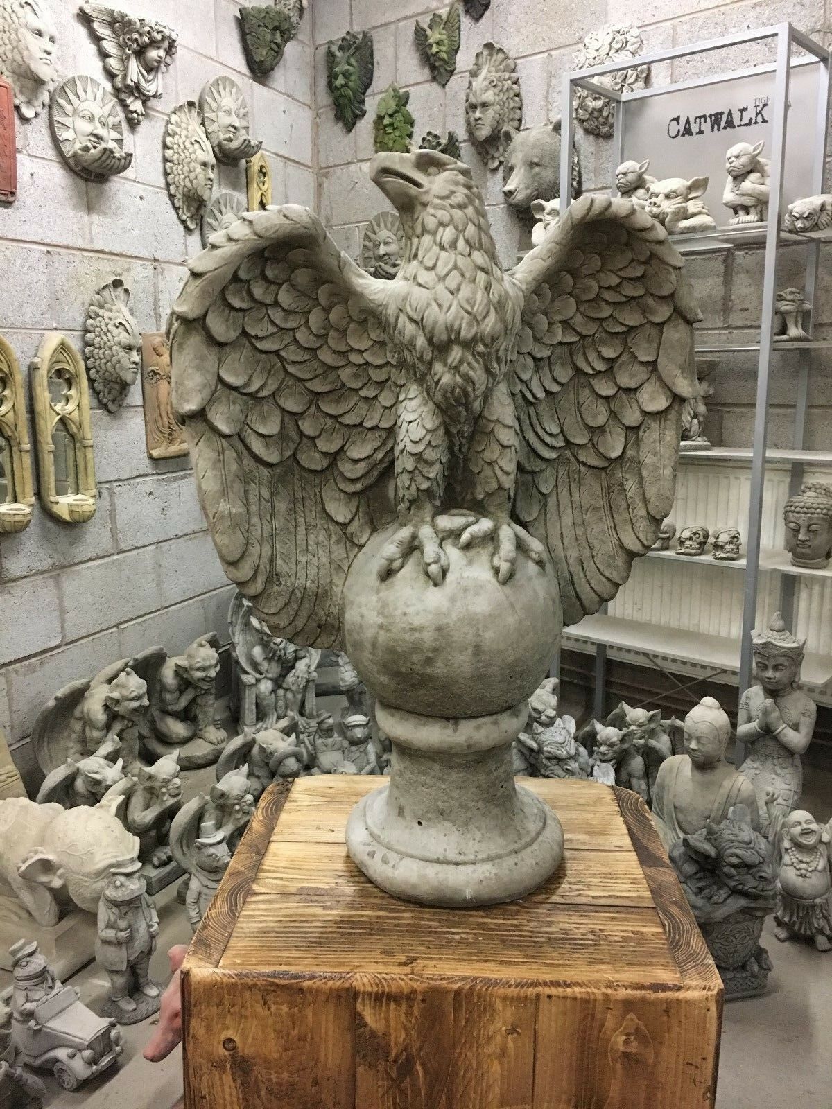Large stone eagle statue with outstretched wings perched on a sphere, ideal for outdoor garden decor and lawn ornamentation.
