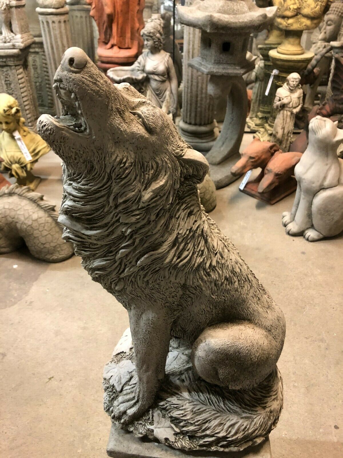 Side view of Howling Wolf Statue with textured fur and rustic finish, mounted on a fleur-de-lis pedestal for garden or patio display.
