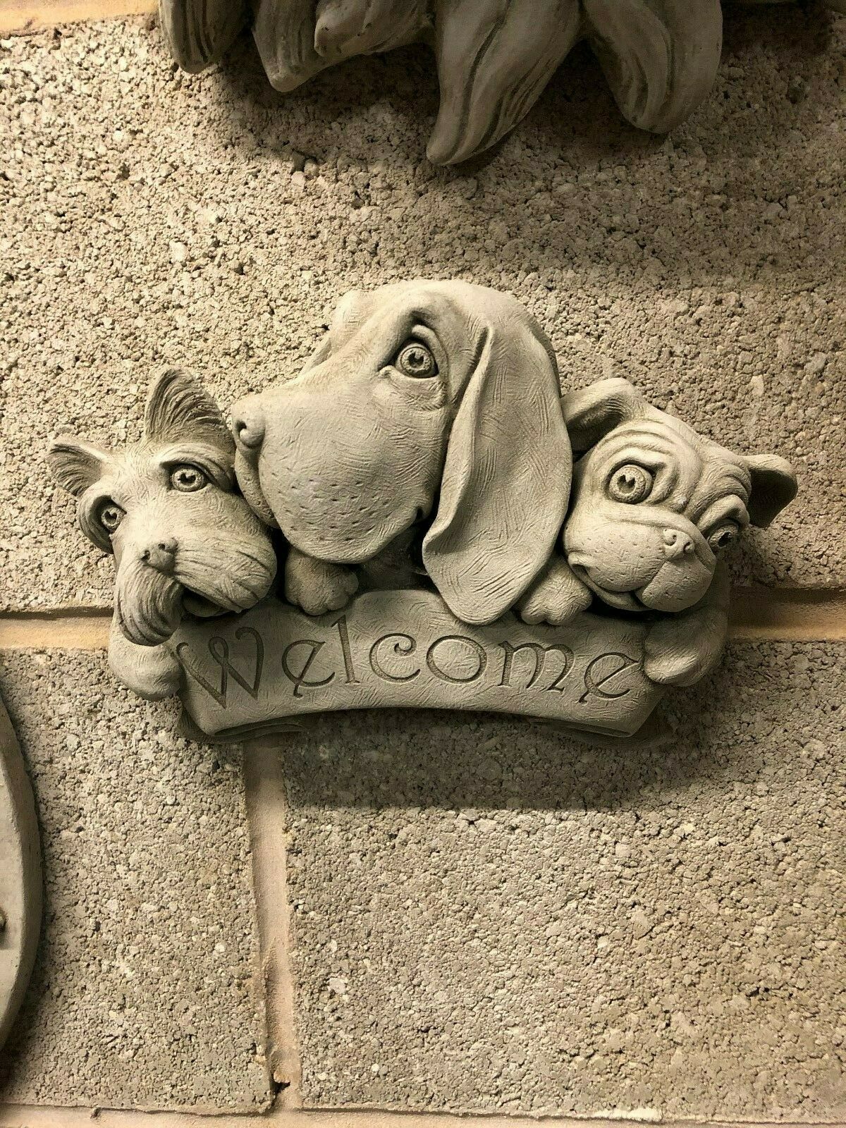 Welcome Dog Garden Plaque - Stone Decor featuring three detailed dog faces sculpted in limestone, ideal for outdoor wall or garden display.