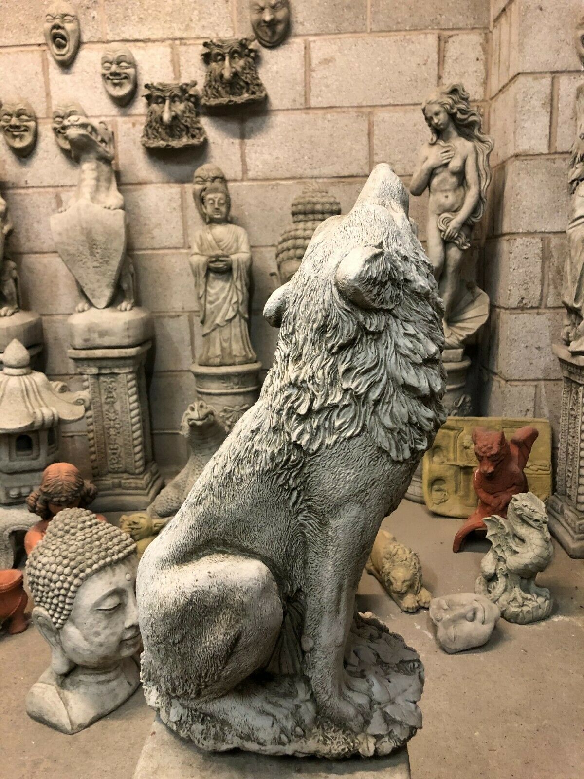 Back view of Howling Wolf Statue on stone pedestal, showcasing detailed fur and solid craftsmanship for home and garden decor.