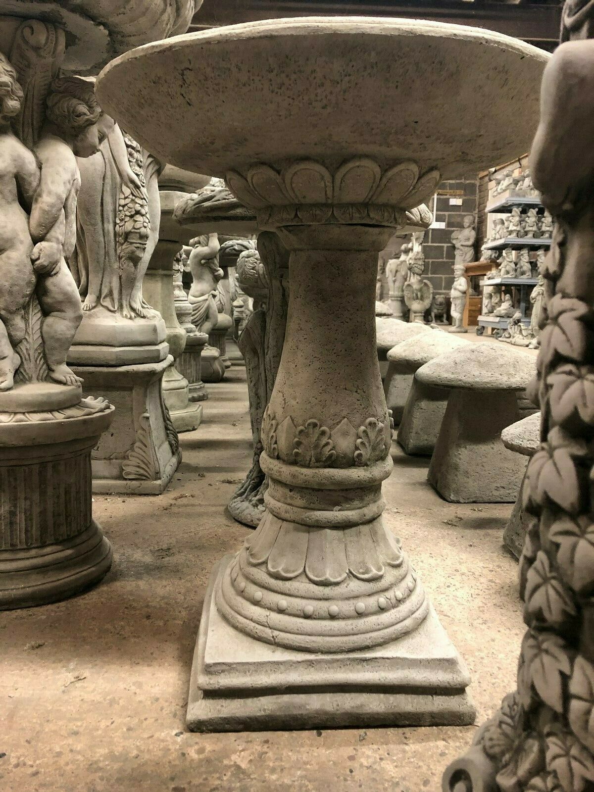 Large durable stone garden bird bath with decorative carved pedestal and antique finish. Perfect for classic garden settings and bird-friendly spaces.