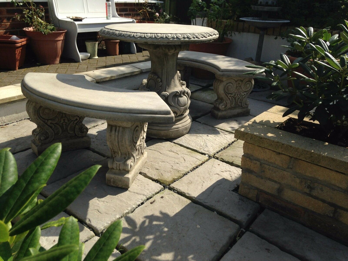 Outdoor stone bench and table set with ornate scroll patterns. Perfect for garden decor and durable all-weather use.