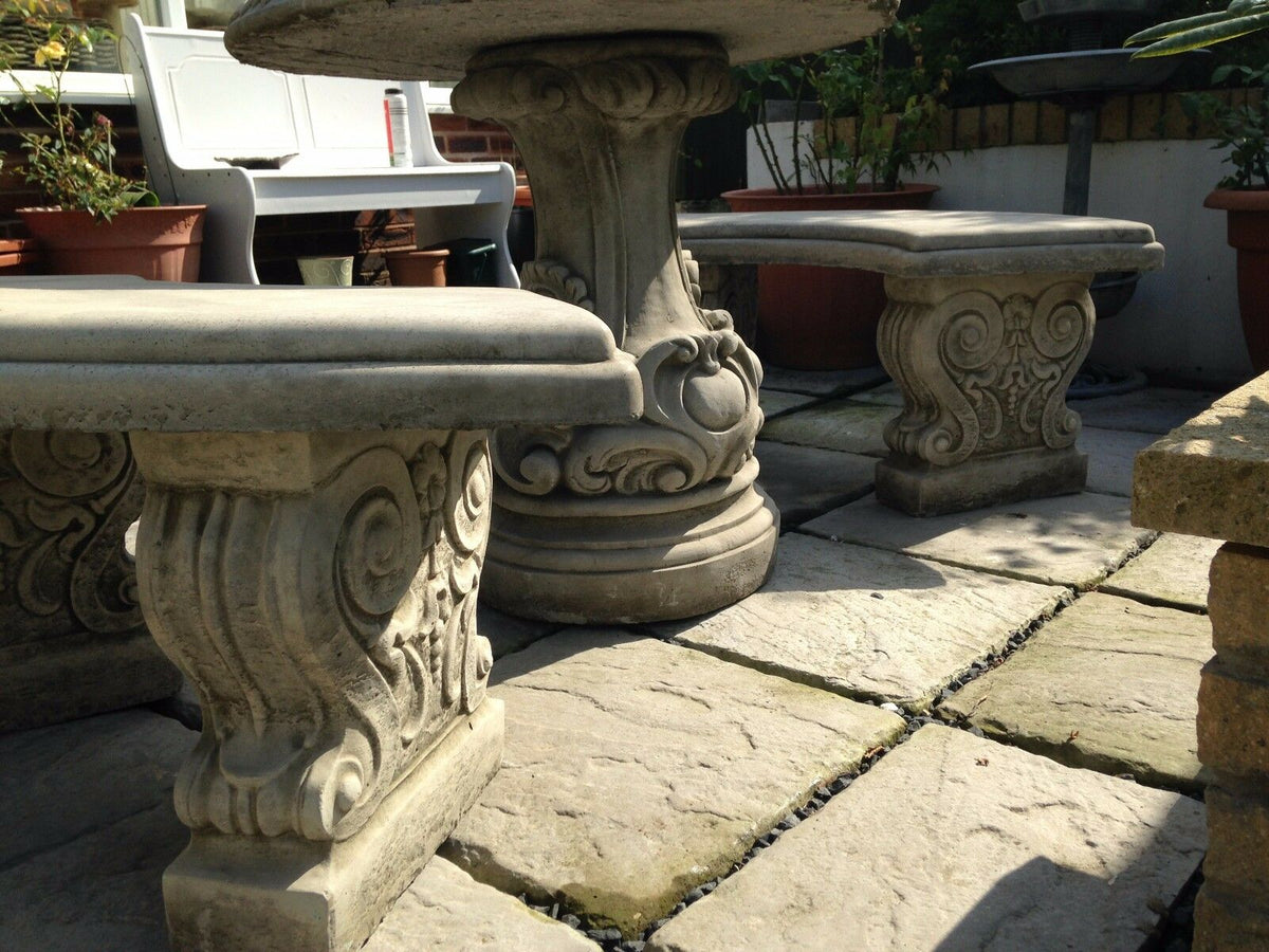 Detailed view of scroll design on stone garden bench and table legs. Heavy solid stone construction for long-lasting garden use.