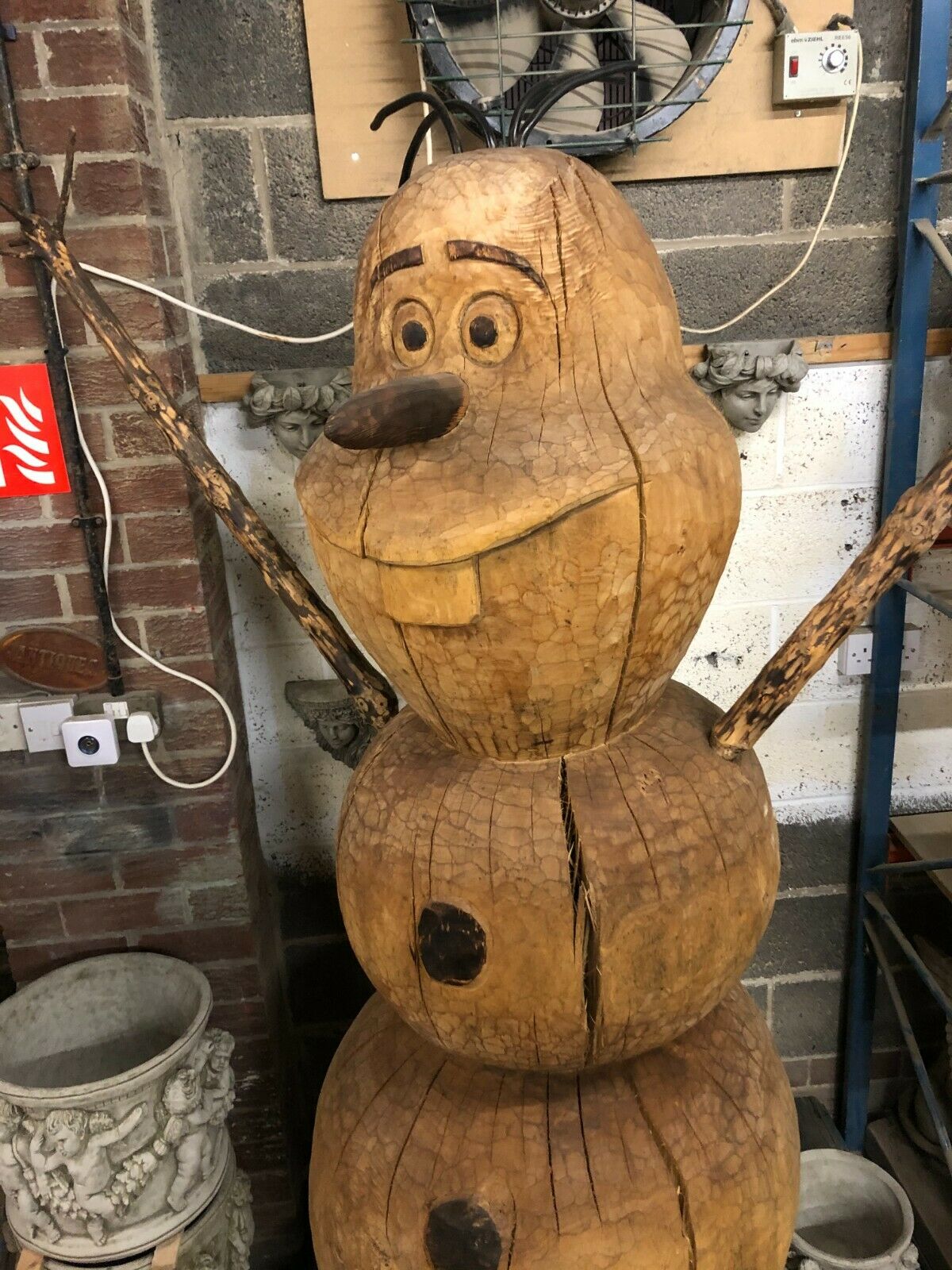 Close-up of the Wooden Olaf Statue's smiling face, showcasing intricate hand-carved details and rustic wood texture.
