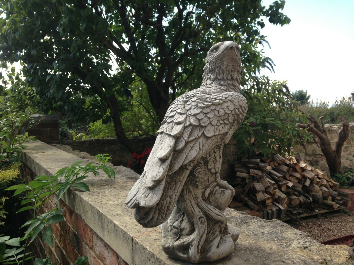 Weatherproof Garden Eagle Statue perched on stone wall, showcasing intricate detailing and antique stone finish for outdoor garden decor.