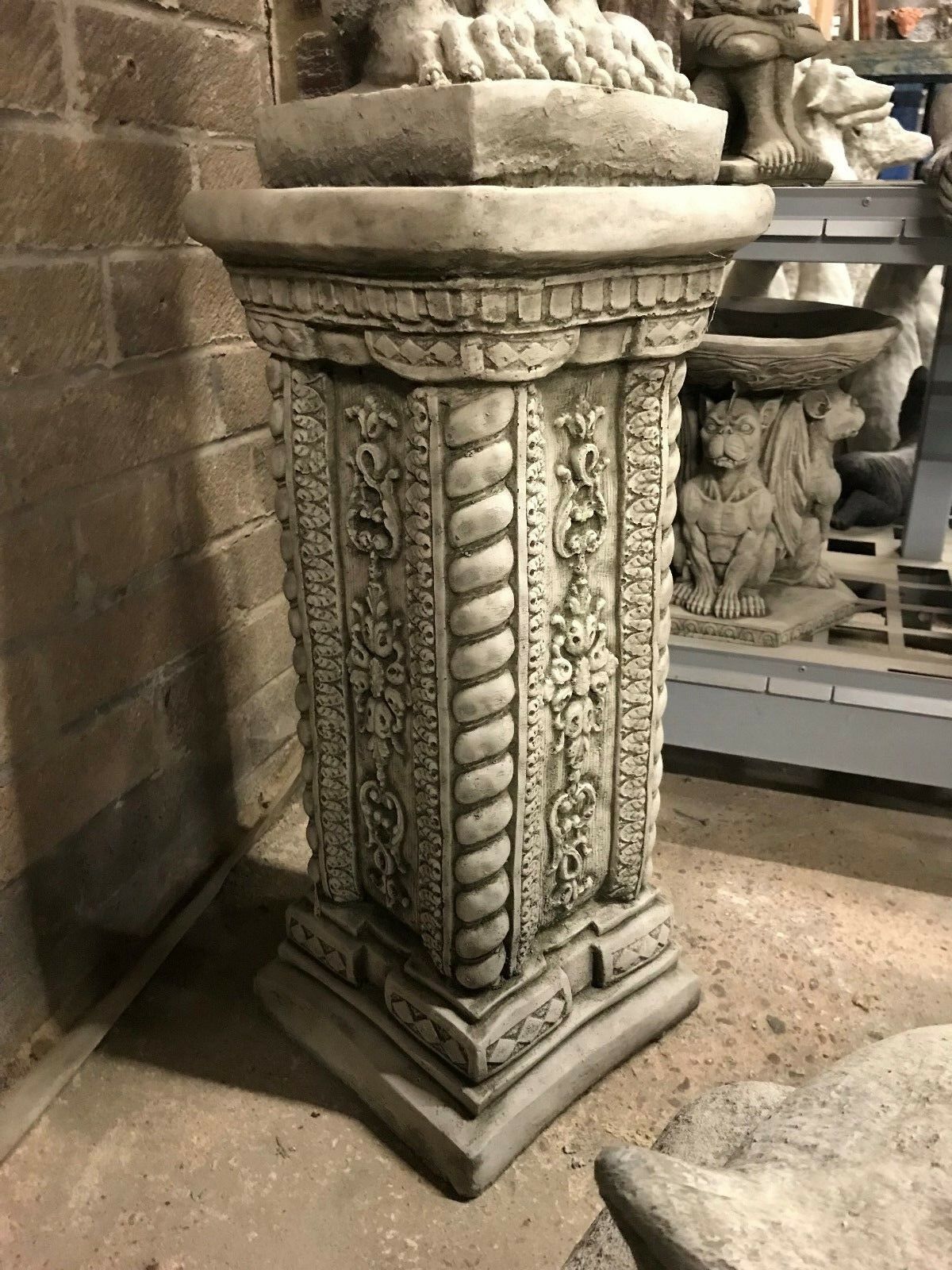 Angled view of the Phoenix statue's pedestal with decorative carvings. Heavy-duty stone base enhances garden sculpture stability and style.