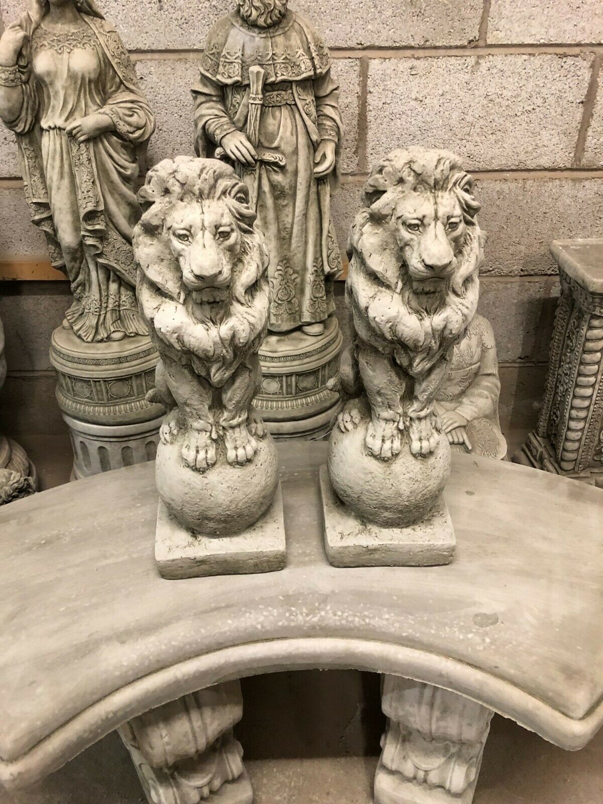 Front-facing pair of stone lion statues on square plinths, ideal for enhancing garden entrances with classic and durable outdoor ornamentation.