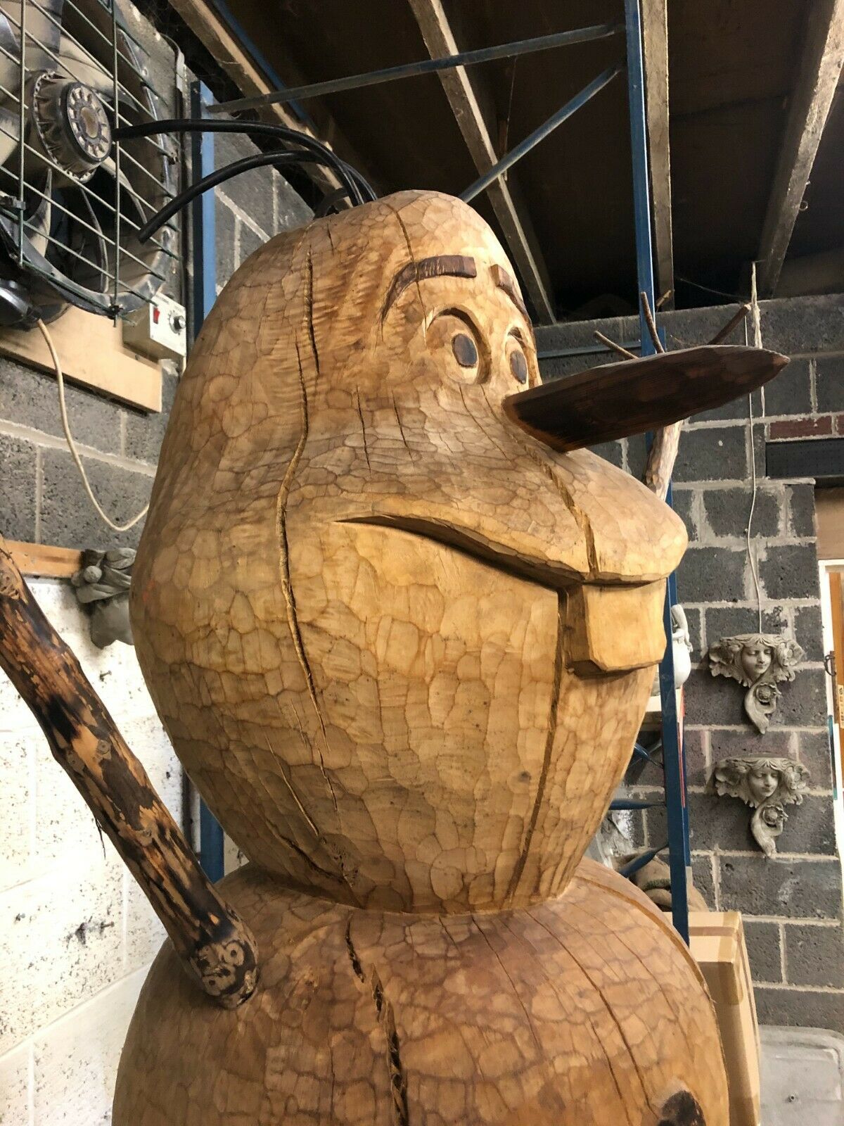 Side view of the Handcrafted Wooden Olaf Garden Statue highlighting the expressive facial features and natural wood grain.