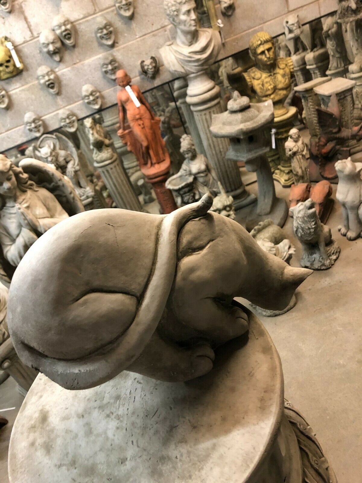 Top-down view of Stone Pouncing Cat Statue showing curved tail and smooth limestone texture for garden ornamentation.