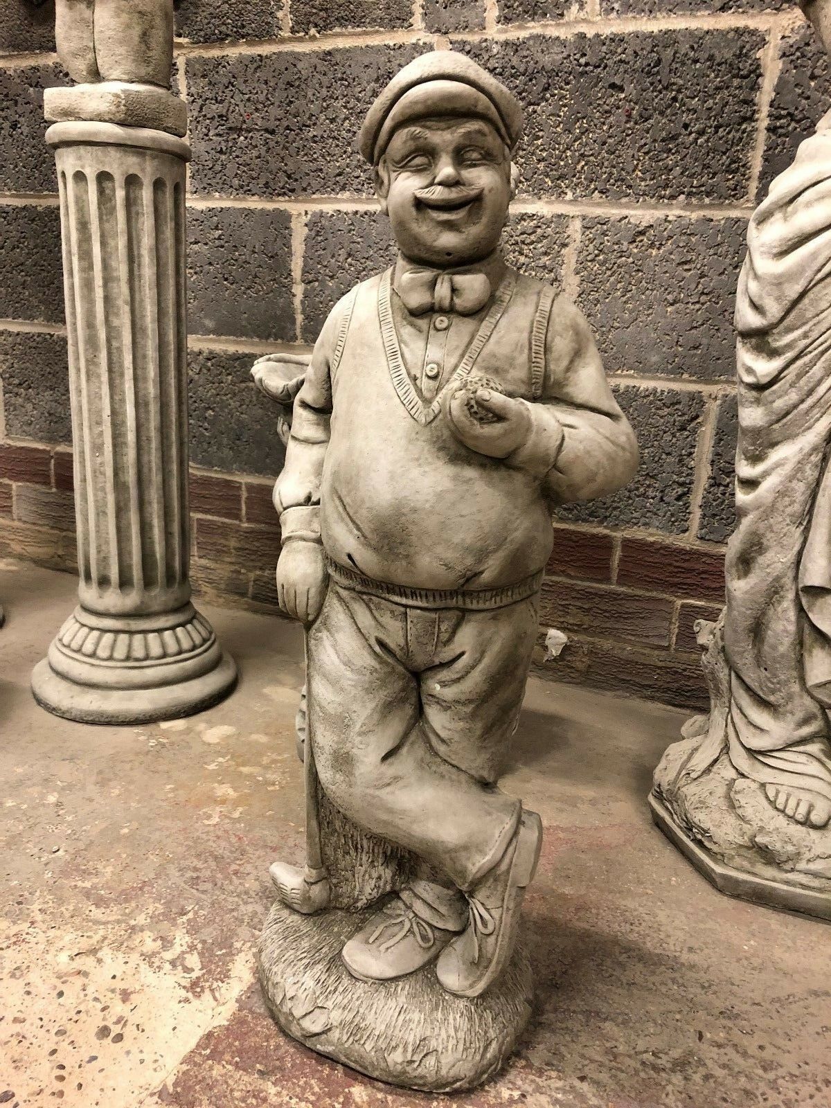 Stone Golfer Garden Statue in antique finish, featuring a smiling man in vintage golf attire holding a ball and club. Ideal for outdoor garden decor.