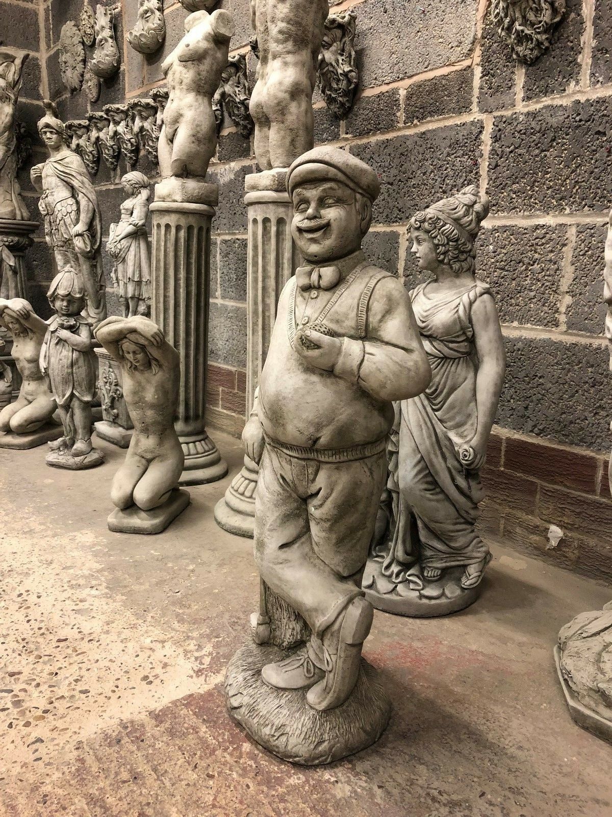 Full view of 76cm Stone Golfer Garden Statue among other sculptures, ideal for classic garden themes and weather-resistant outdoor ornamentation.