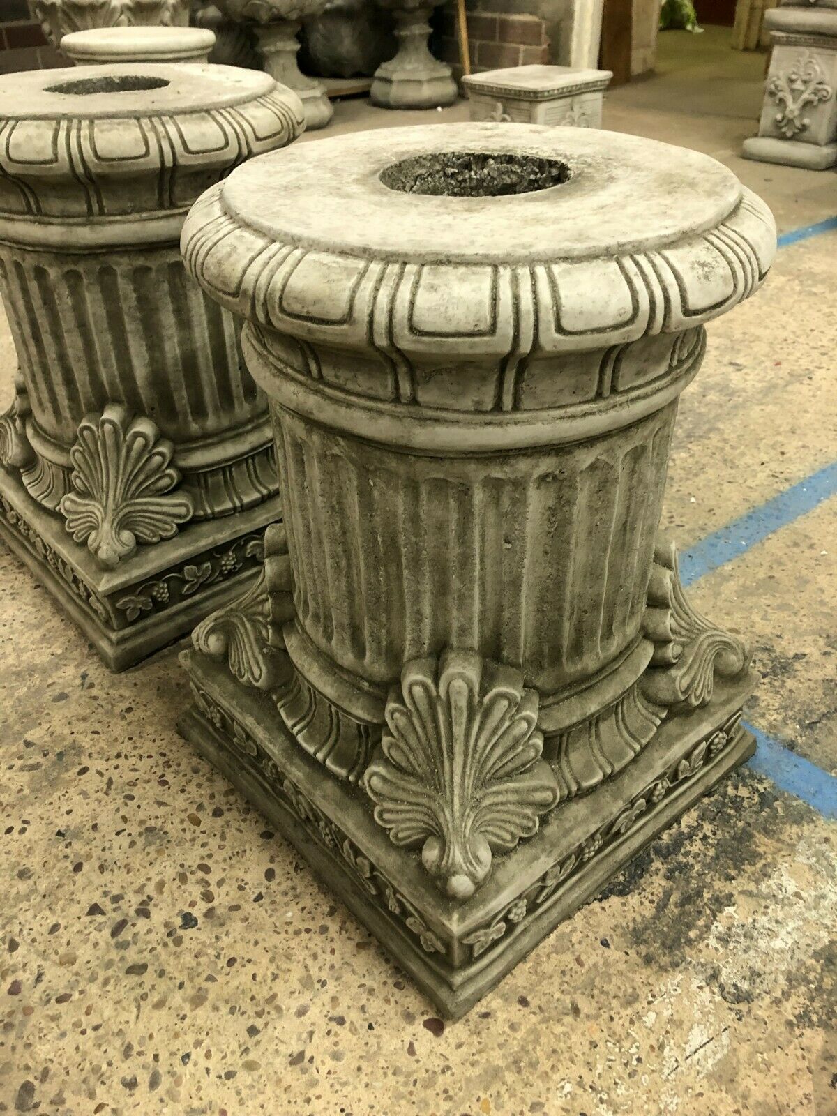 Detailed view of antique grey stone plinths with floral and shell motifs, enhancing traditional garden aesthetics with durable limestone craftsmanship.