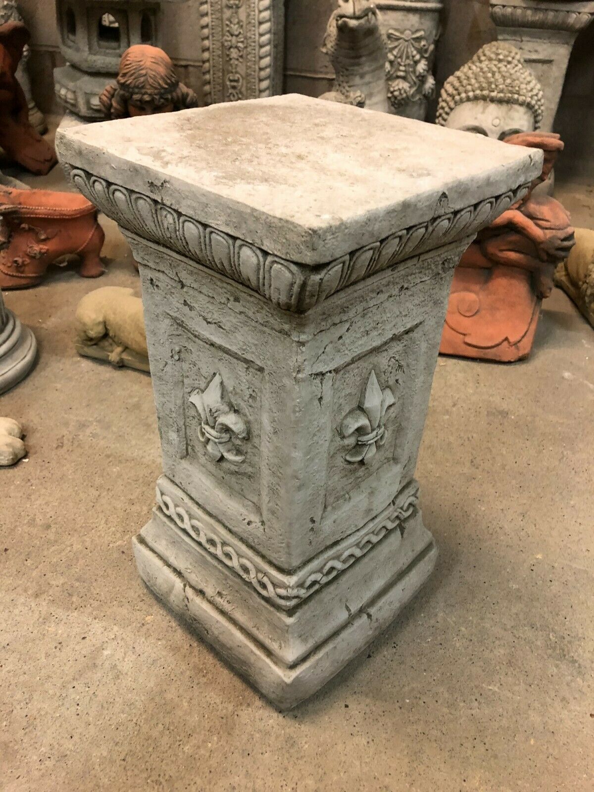 Stone Fleur De Lis Pedestal in antique grey finish, ideal for outdoor garden sculptures. Weather-resistant limestone plinth with ornate detailing.