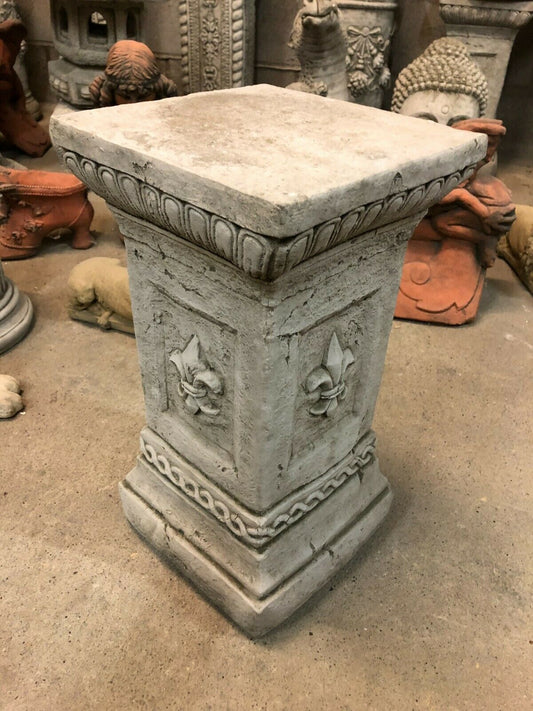 Stone Fleur De Lis Pedestal in antique grey finish, ideal for outdoor garden sculptures. Weather-resistant limestone plinth with ornate detailing.