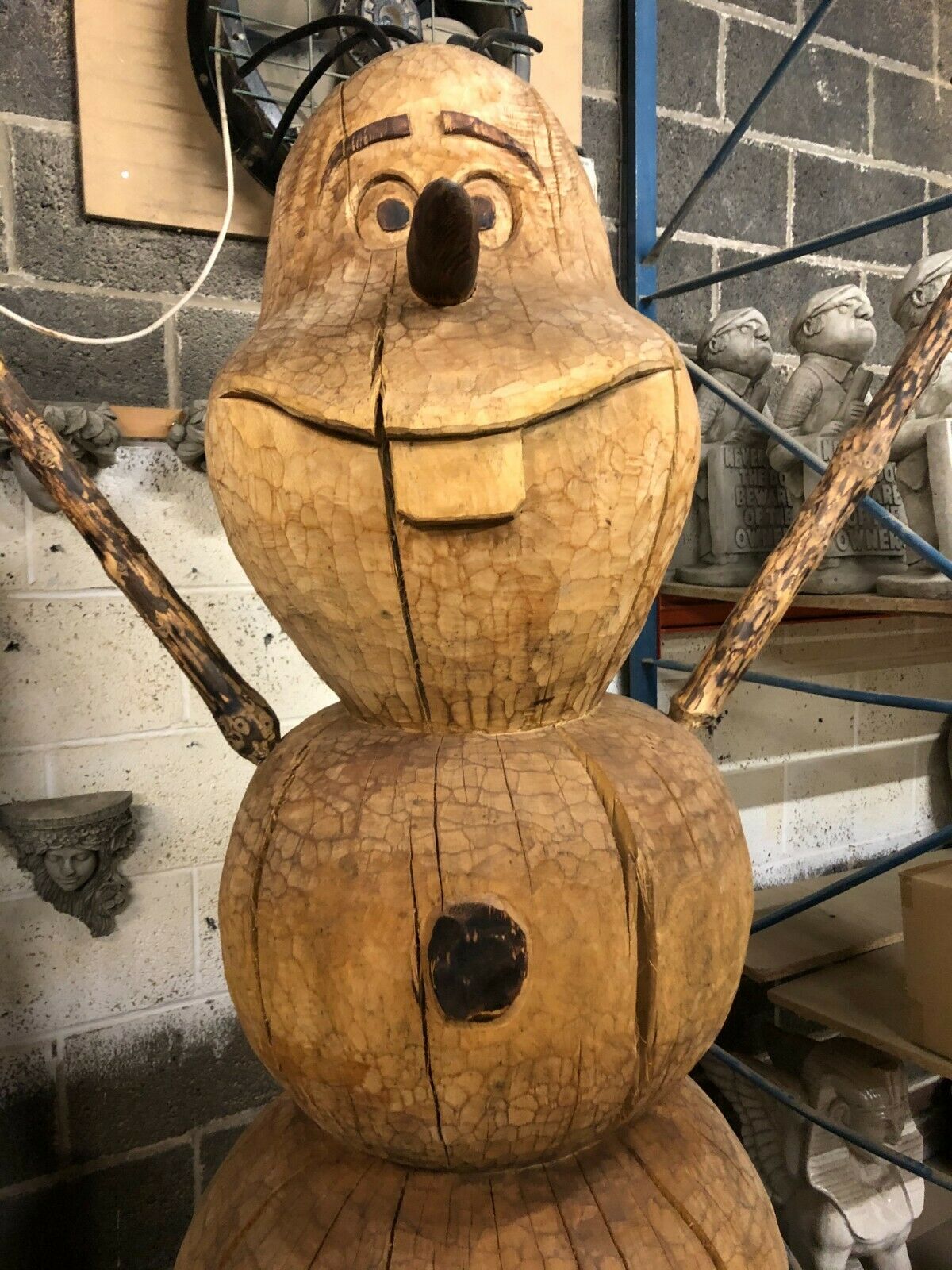 Front view of the Wooden Olaf Sculpture showing button details and twig arms, ideal for themed garden decoration.