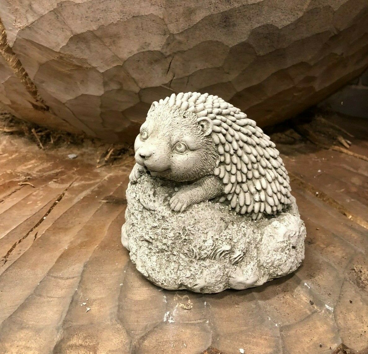 Stone Baby Hedgehog Ornament with antique grey finish resting on textured rock base, ideal for garden decor or flower beds.