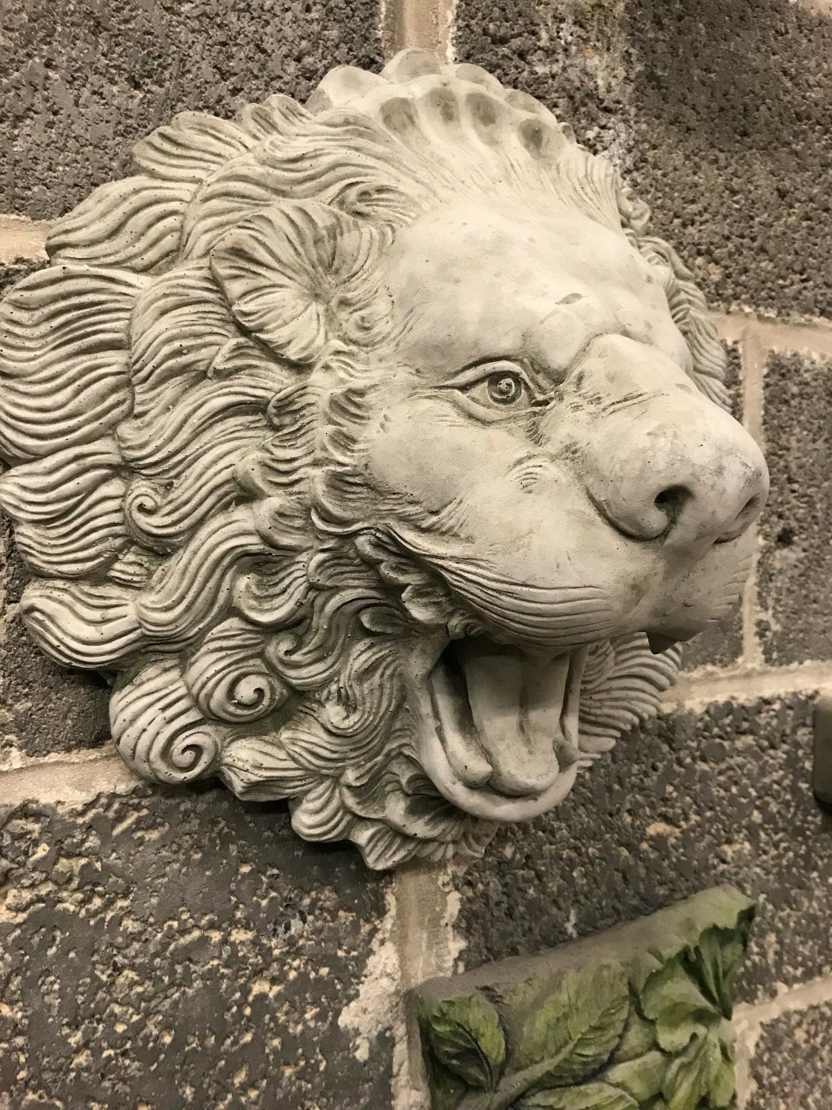 Close-up of roaring lion head garden spout in stone finish. A striking antique water feature for patios or garden walls.