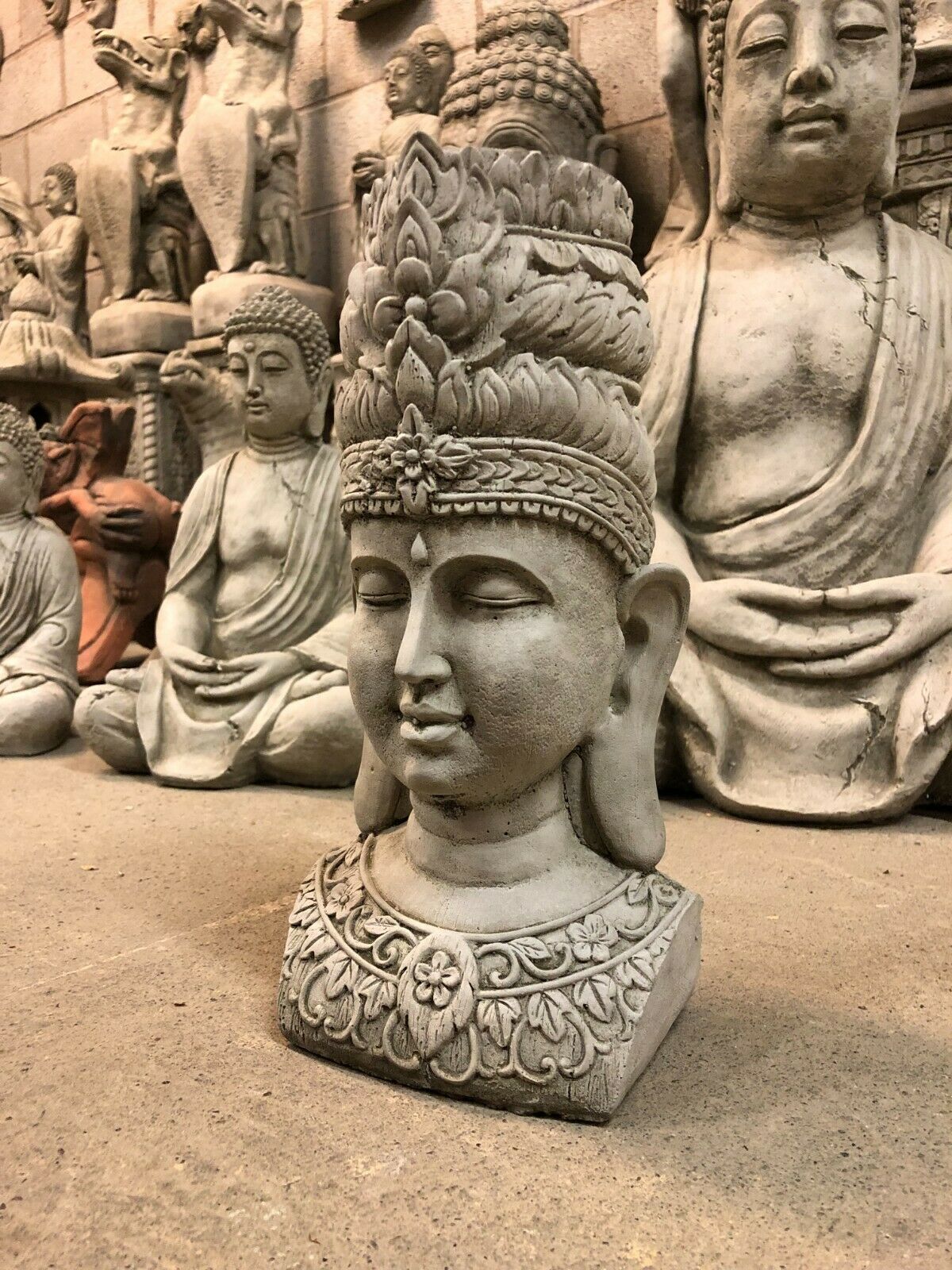 Tranquil Stone Buddha Bust Garden Ornament with intricate floral crown, ideal for outdoor decor in peaceful garden settings.