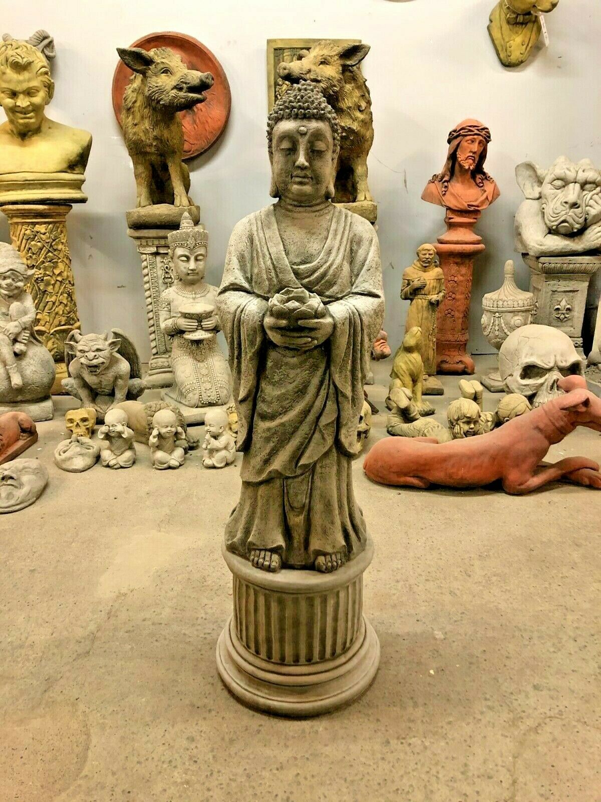 Durable stone Buddha statue with candle holder, standing on a fluted pedestal, ideal for garden or patio decor.