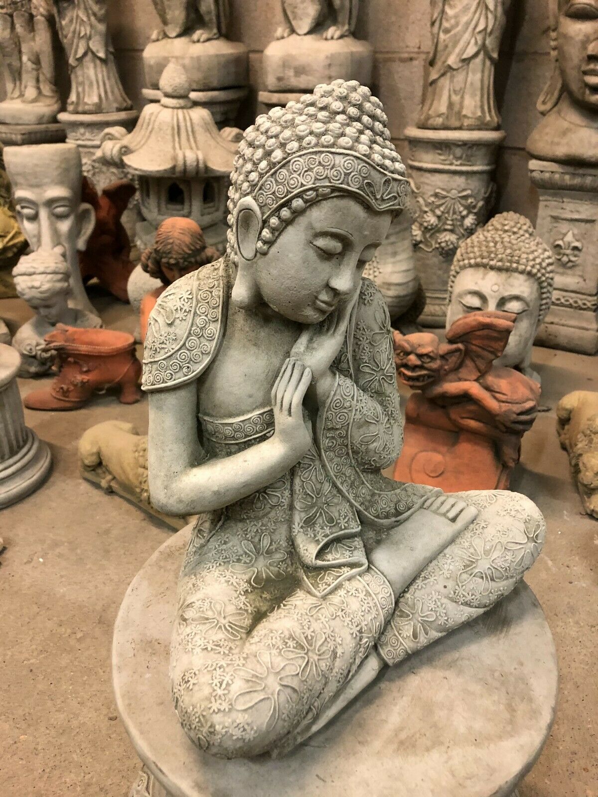 Durable Stone Buddha Garden Ornament with intricate floral carvings, hands resting on cheek. Perfect for patios, lawns, or zen garden spaces.