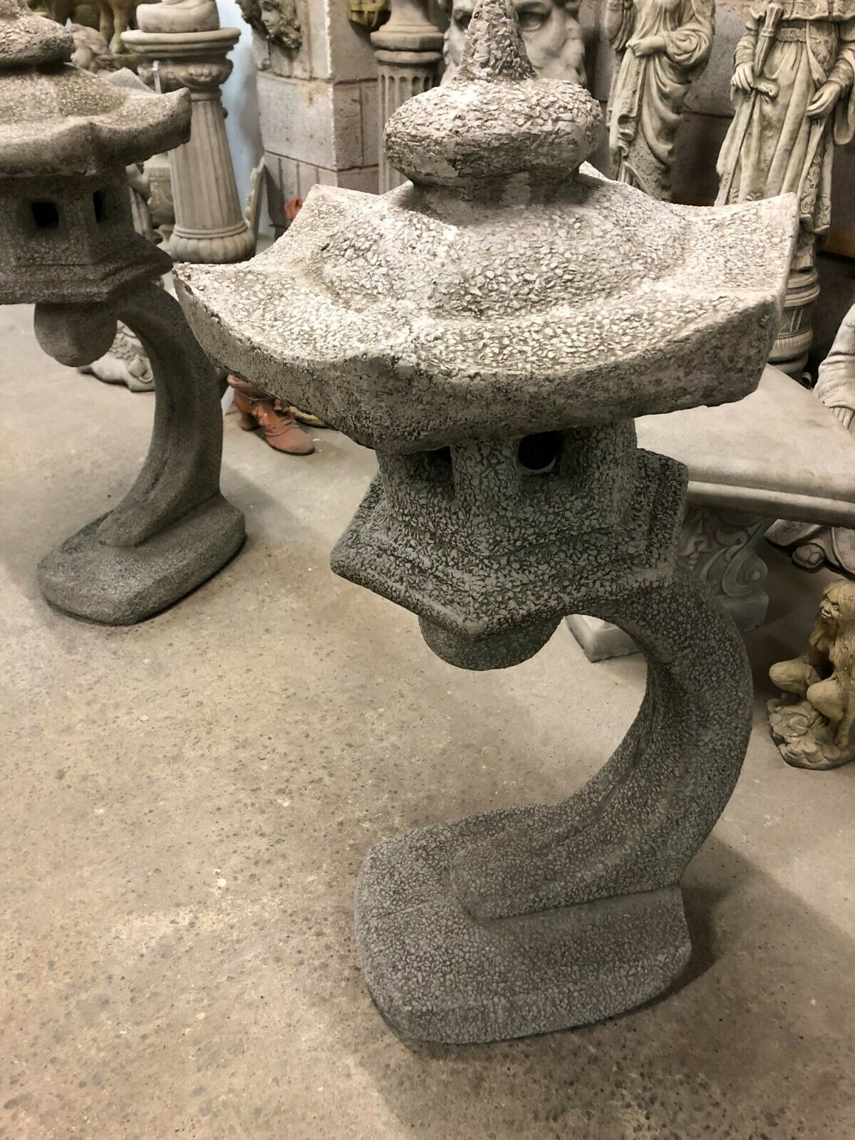 Close-up of antique grey stone pagoda lantern statue showing detailed craftsmanship and curved base for garden ornamentation.