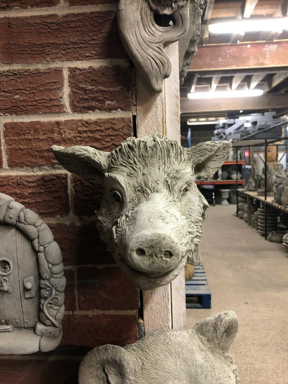 Stone Wild Boar Wall Plaque with rustic limestone finish, mounted on a brick wall. Ideal as a Wild Boar Wall Plaque - Rustic Stone Ornament | Easy Hang.