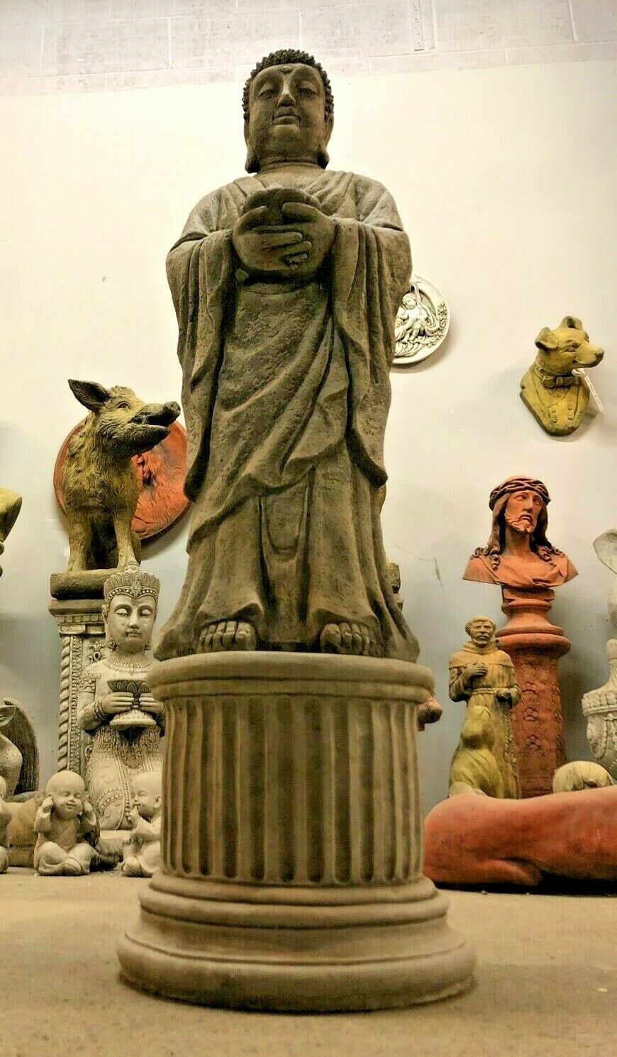 Low-angle shot of limestone Buddha statue on a plinth, designed for candle or tealight placement in garden settings.