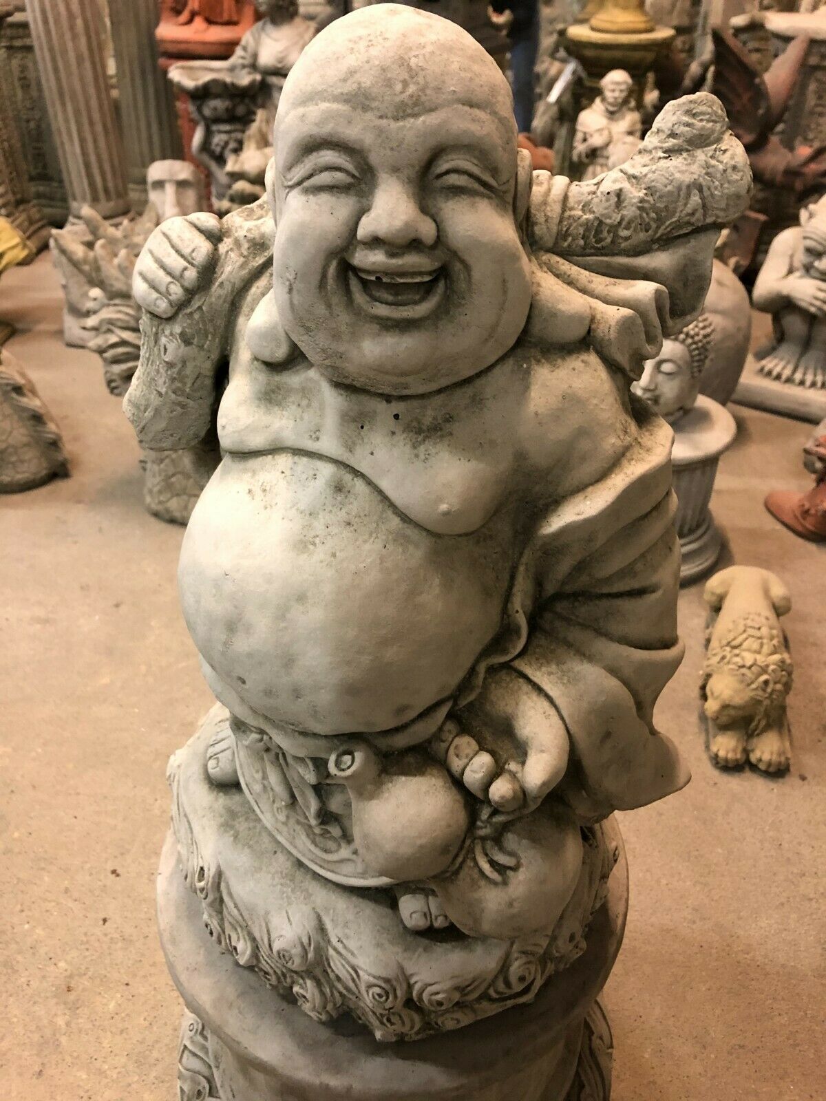 Close-up of Stone Laughing Buddha Garden Statue with Plinth, showcasing detailed facial expression and limestone texture for outdoor spiritual ambiance.