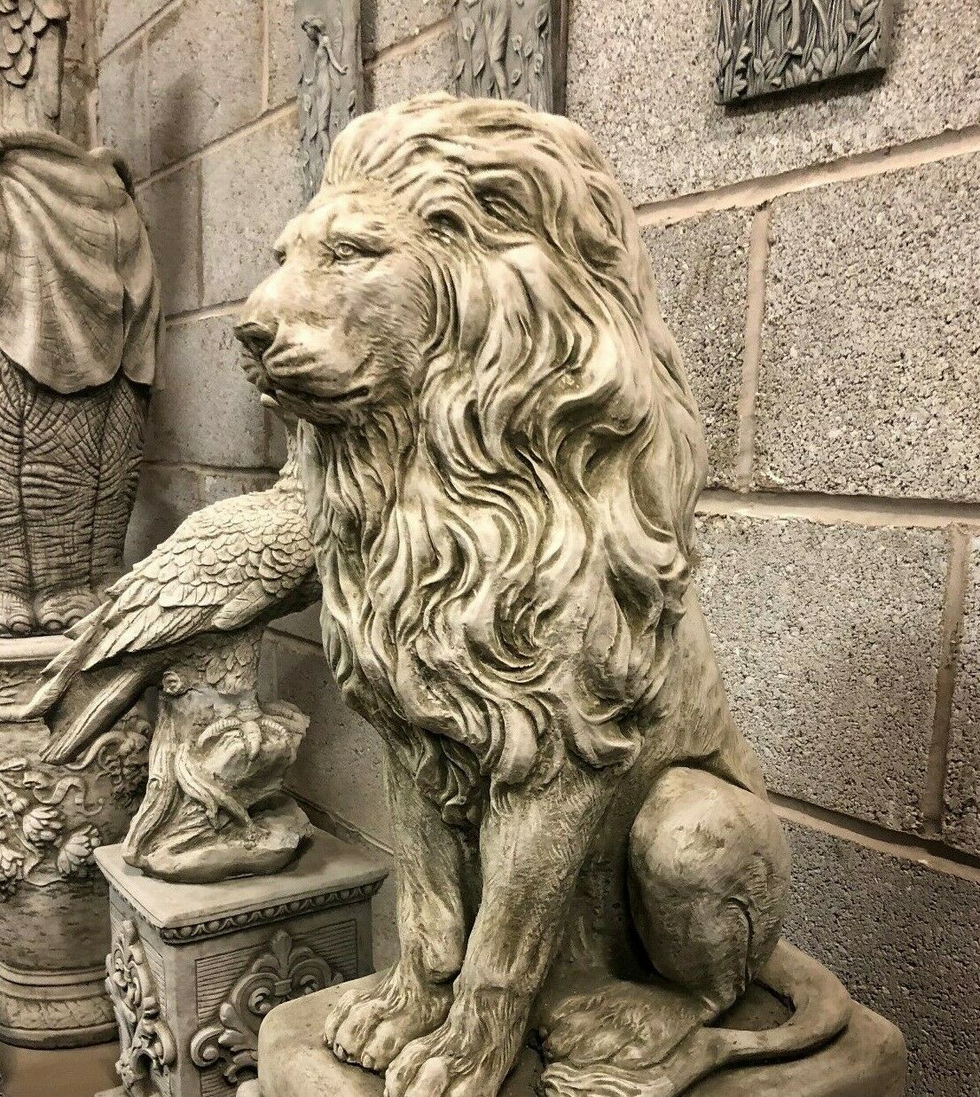 Side profile of stone lion statue on plinth, ideal for garden entrances or decorative landscaping with a majestic theme.