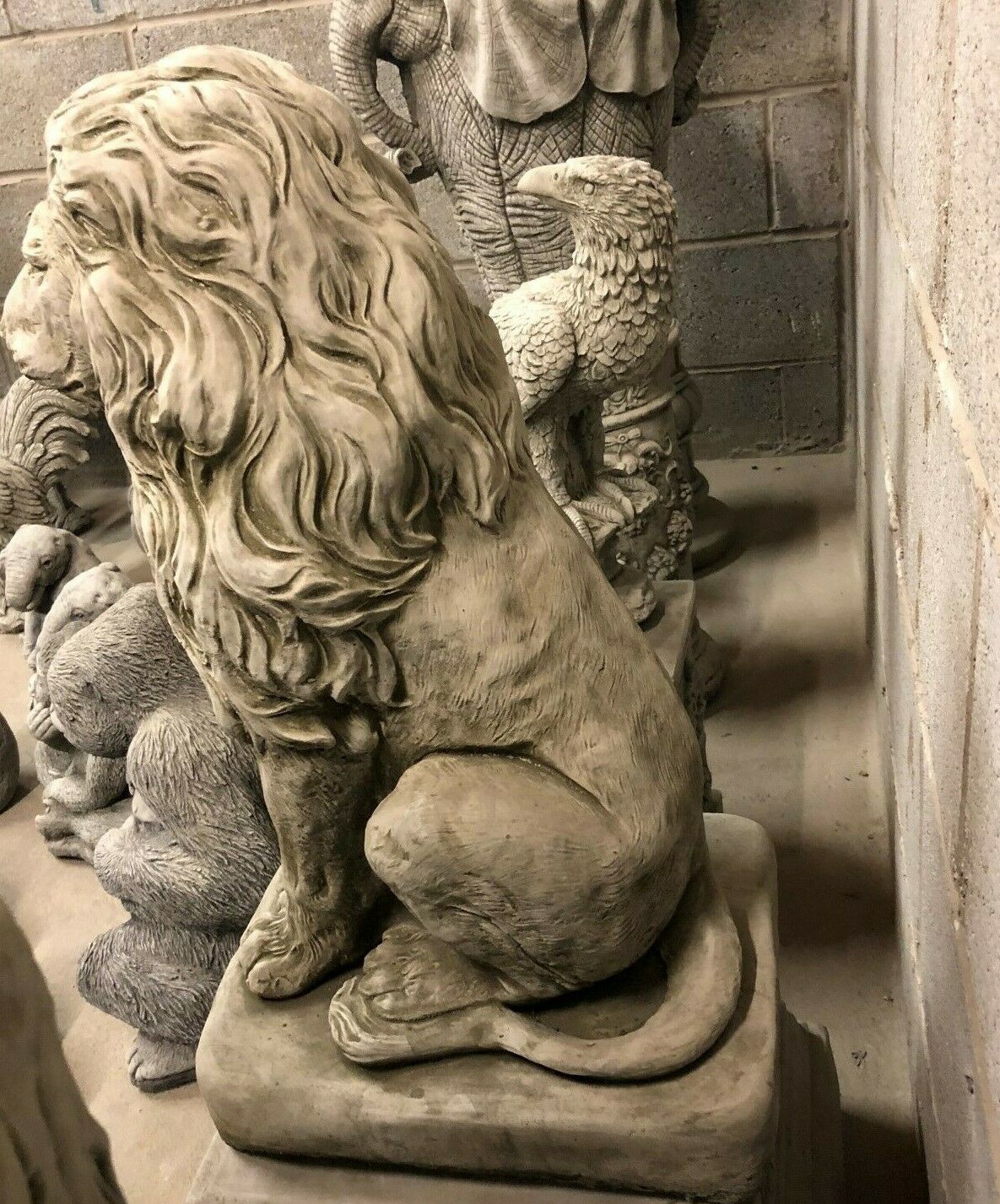 Rear side view of lion statue showing tail and muscular form, crafted in stone for durable garden ornament use.