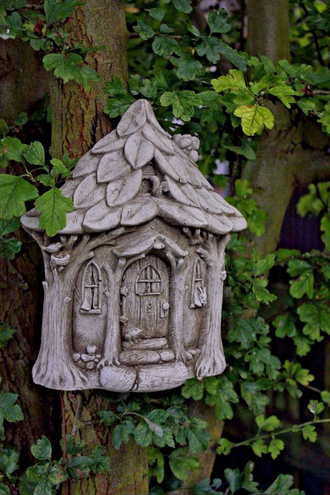 Stone Fairy Garden House plaque attached to tree in leafy garden. Durable limestone ornament adds charm to outdoor wall or tree settings.