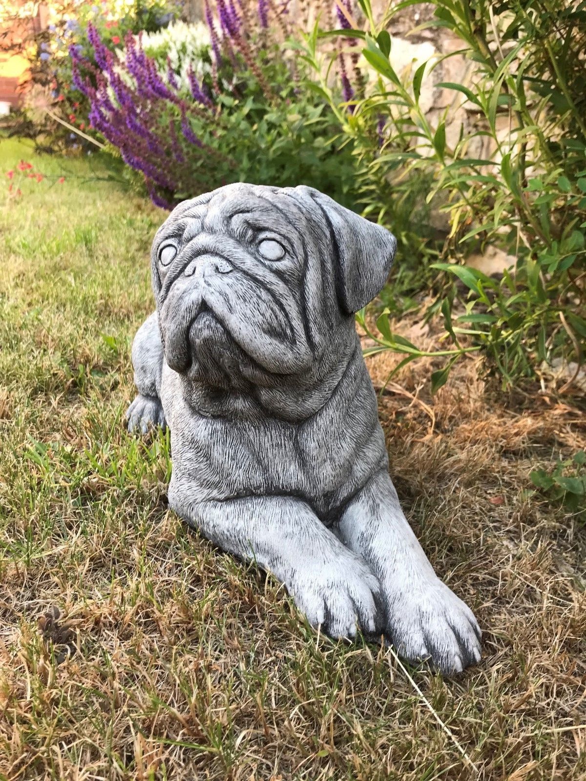 Lifelike Stone Pug Sculpture - Garden Ornament positioned in a garden setting, adding charm and character to outdoor spaces.
