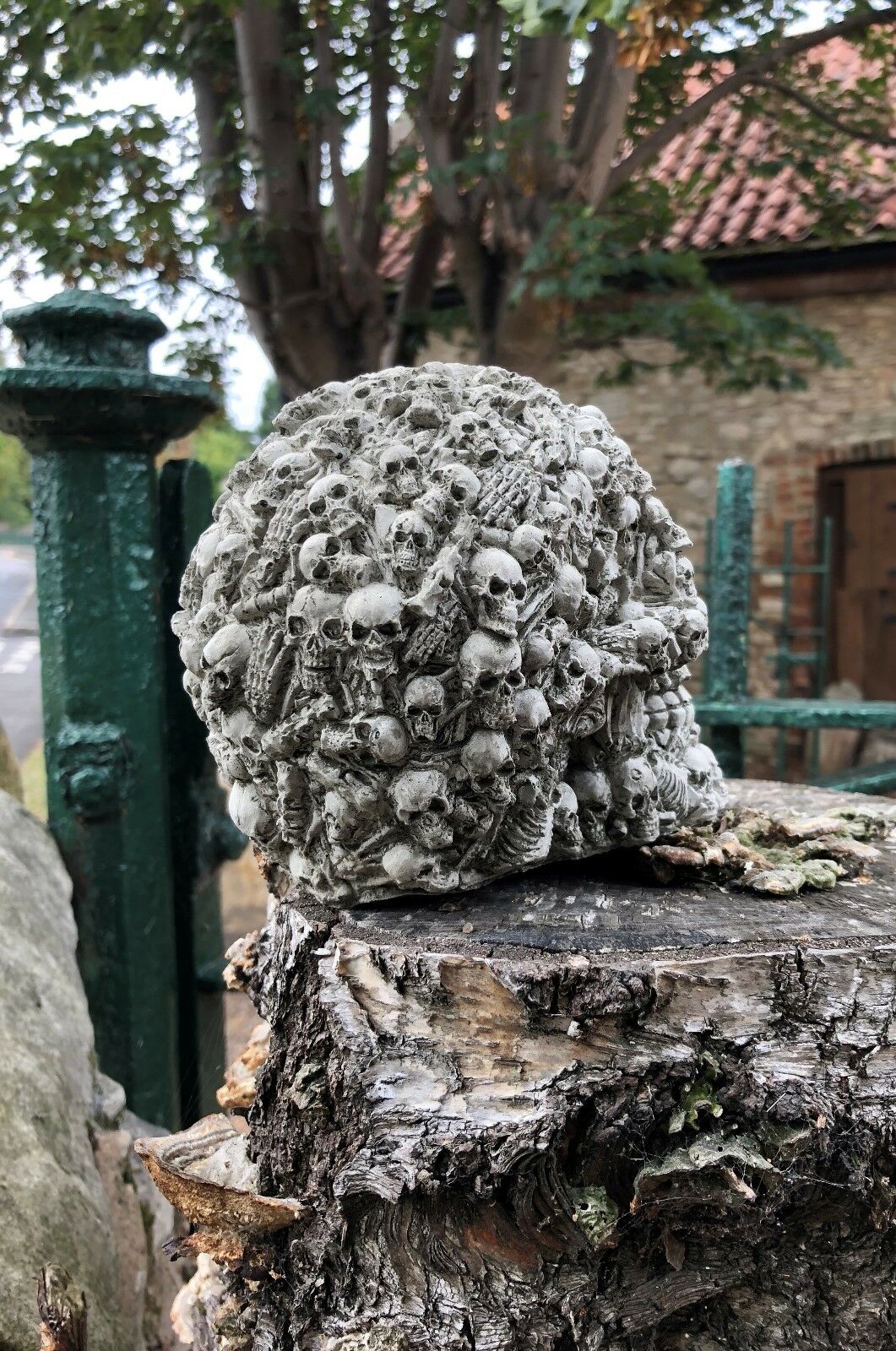 Back view of Stone Skull Garden Ornament featuring dense skull patterns. Durable limestone sculpture for unique outdoor decoration.